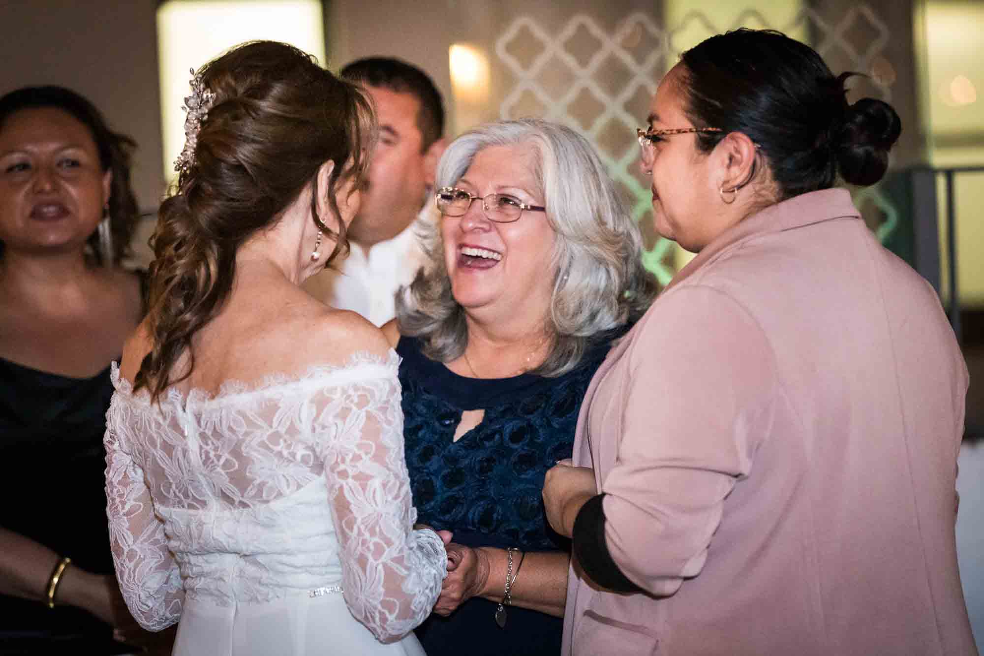 Bride and guests smiling and talking with one another on the Sky Terrace during a wedding reception