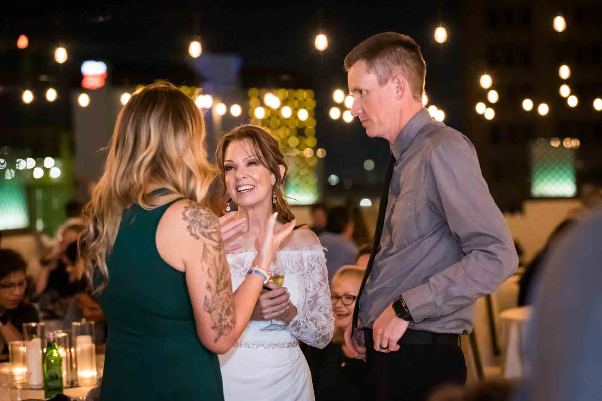 Bride and guests smiling and talking with one another on the Sky Terrace during a wedding reception