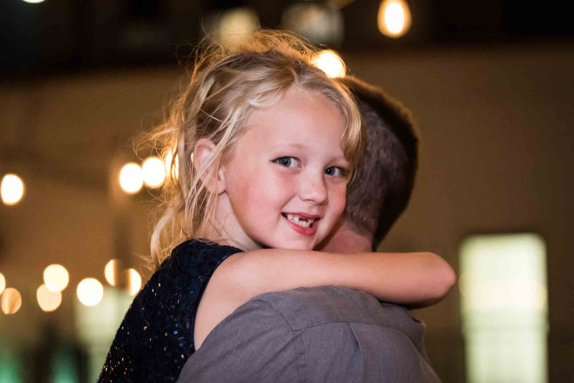 Little blonde girl being carried by father during St. Anthony Hotel wedding reception