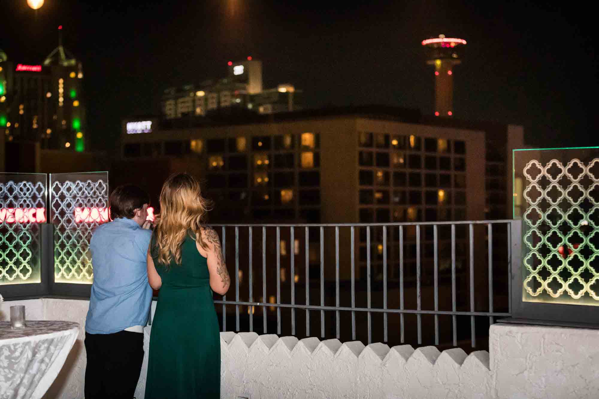 Couple looking over railing at Tower of the Americas and San Antonio skyline during St. Anthony Hotel wedding reception