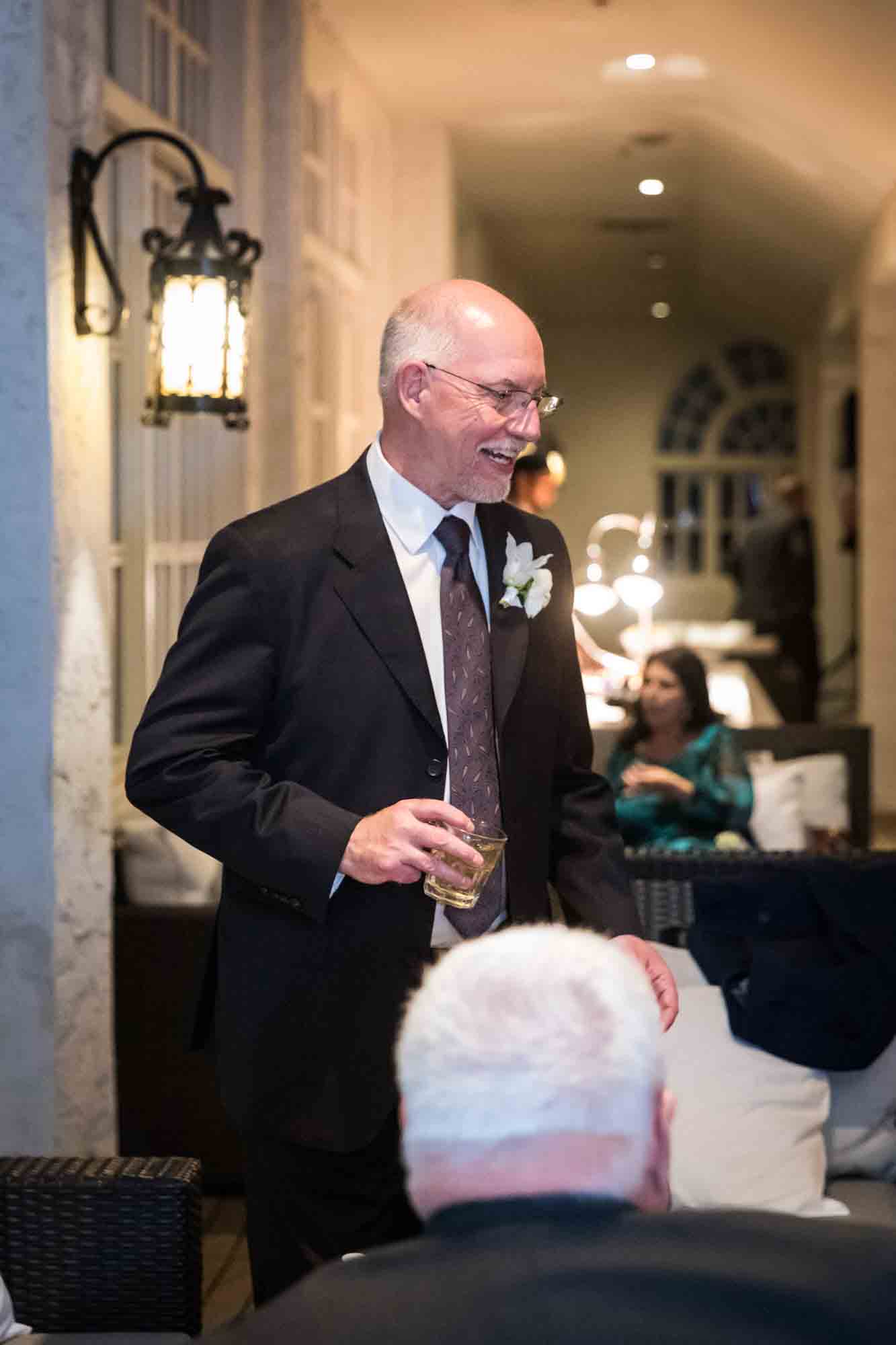 Groom speaking with guests while holding drink in hand during St. Anthony Hotel wedding reception