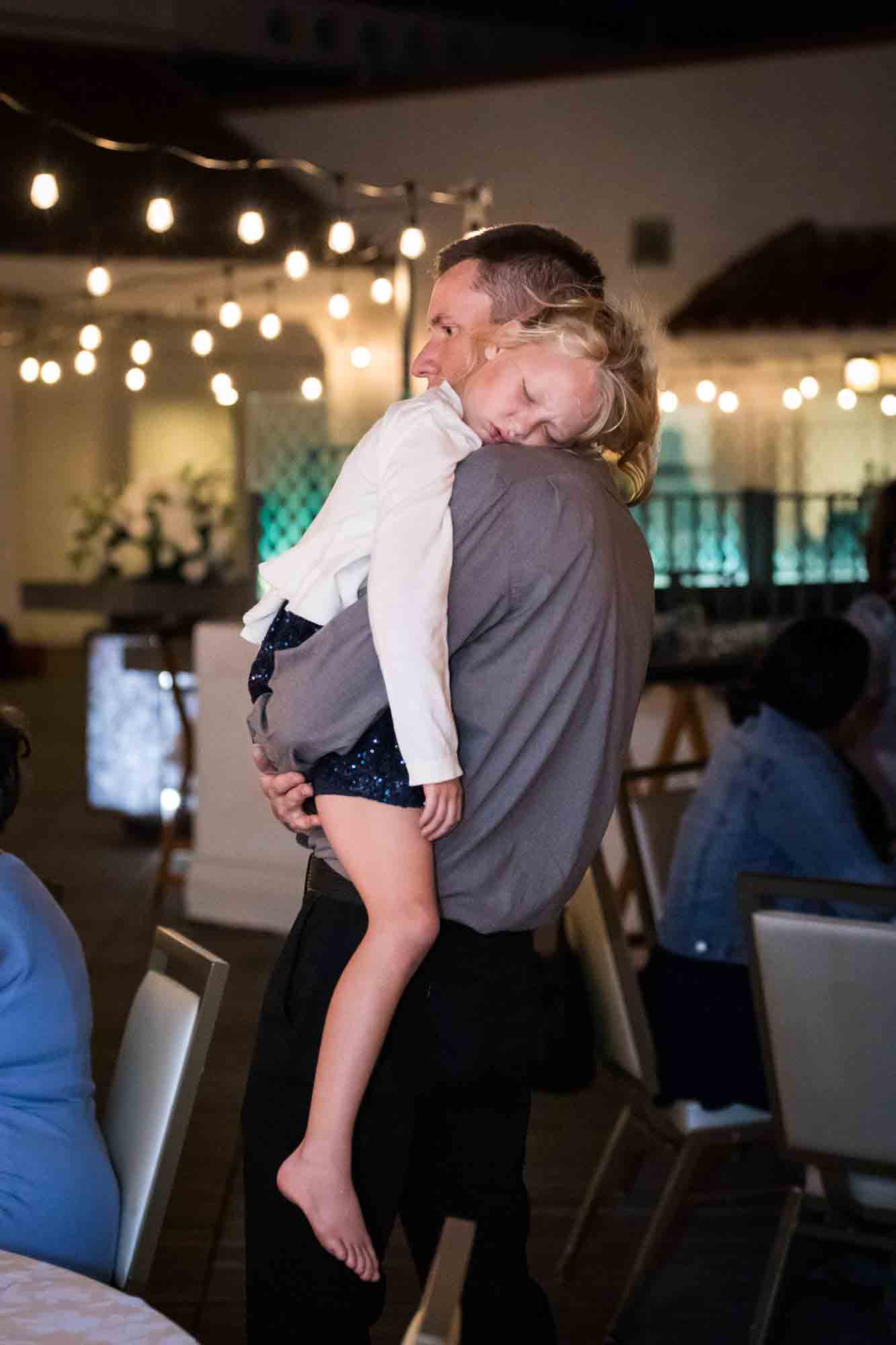 Father holding sleeping little girl during St. Anthony Hotel wedding reception