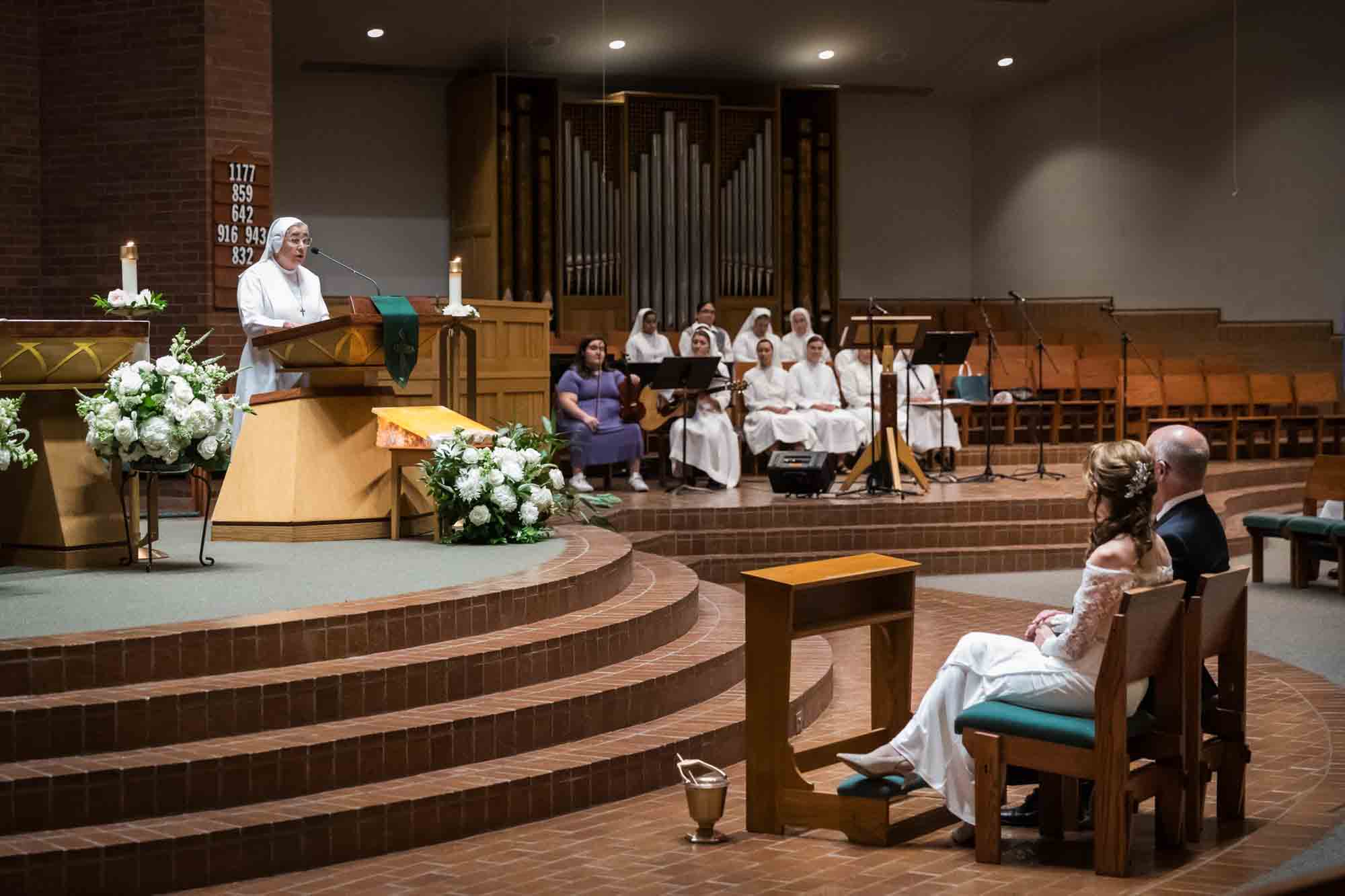 Nun speaking at podium in front of bride and groom and guests at a St. Mark the Evangelist Catholic Church wedding