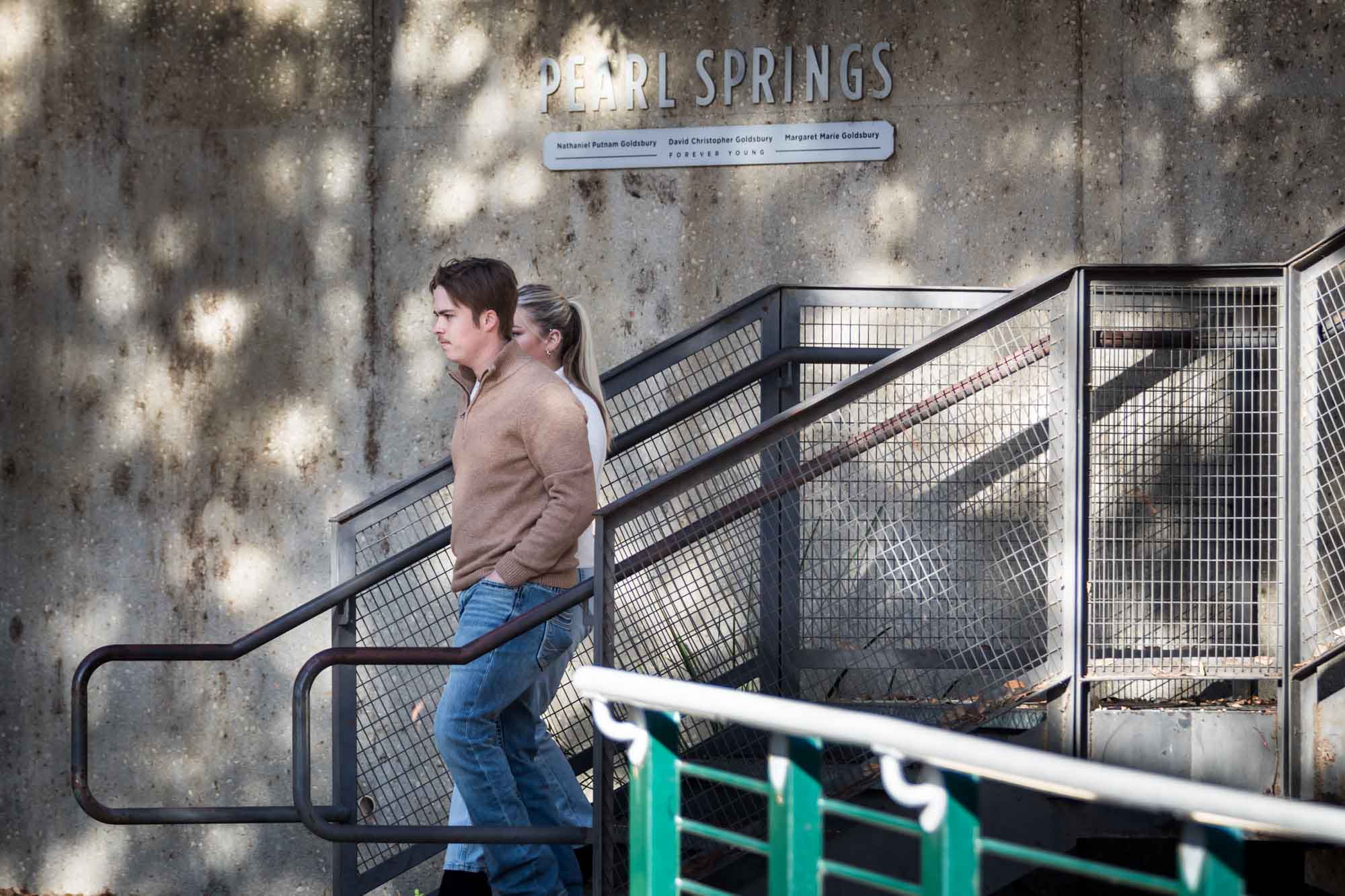 Couple walking down stairs with Pearl Springs sign in background for an article on the importance of timing for a surprise proposal