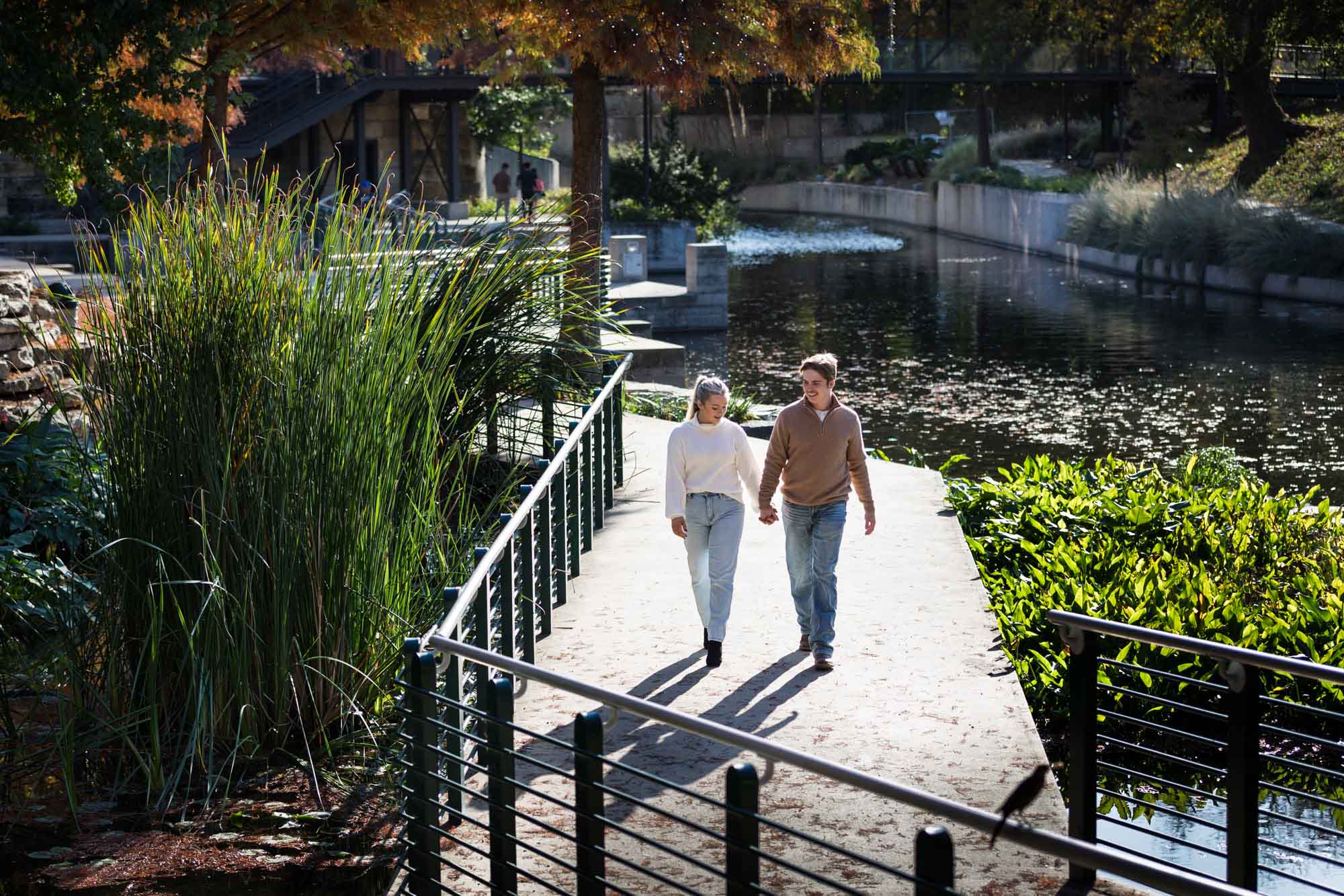 Couple holding hands walking up pathway along Riverwalk at the Pearl