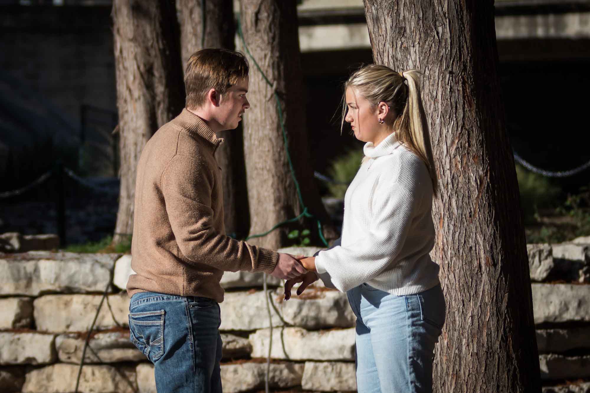 Man in brown sweater speaking to woman in white sweater for an article on the importance of timing for a surprise proposal