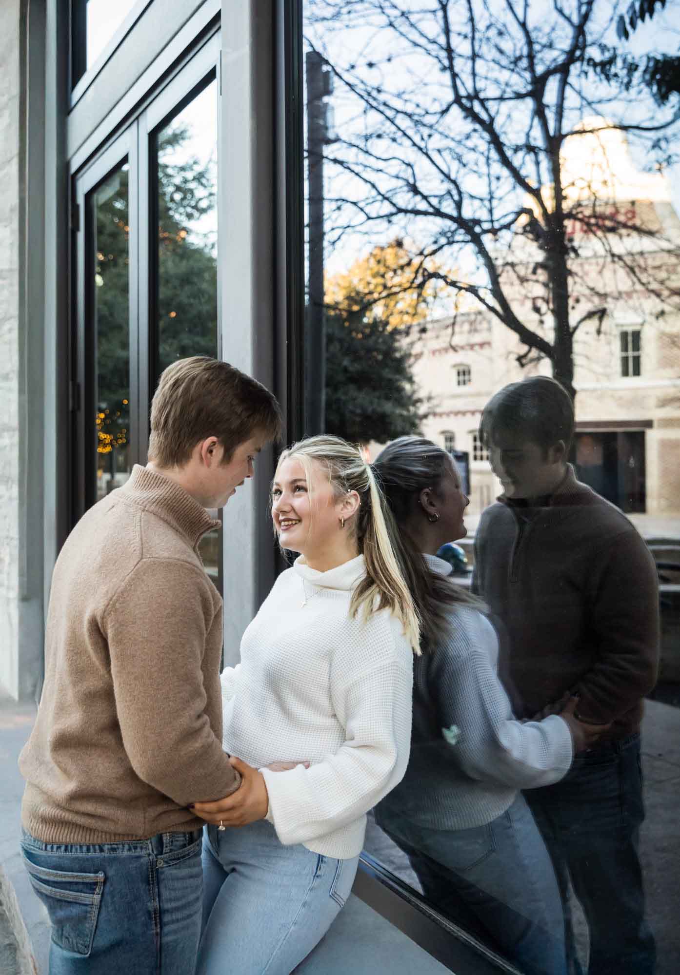 Couple looking at each other while reflected in glass window for an article on the importance of timing for a surprise proposal