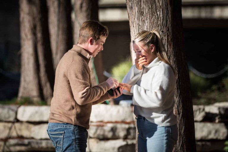 Man putting ring on finger of woman wearing white sweater for an article on the importance of timing for a surprise proposal