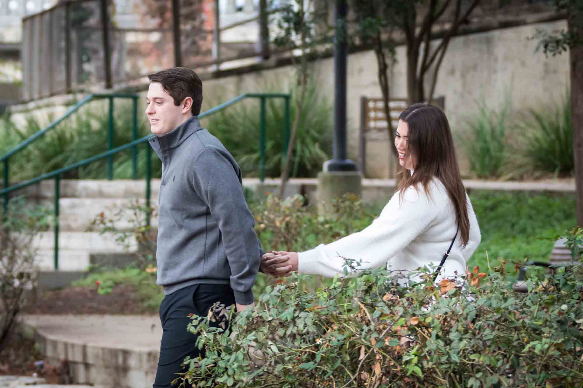 Man leading girlfriend to little island during a surprise proposal at the Pearl