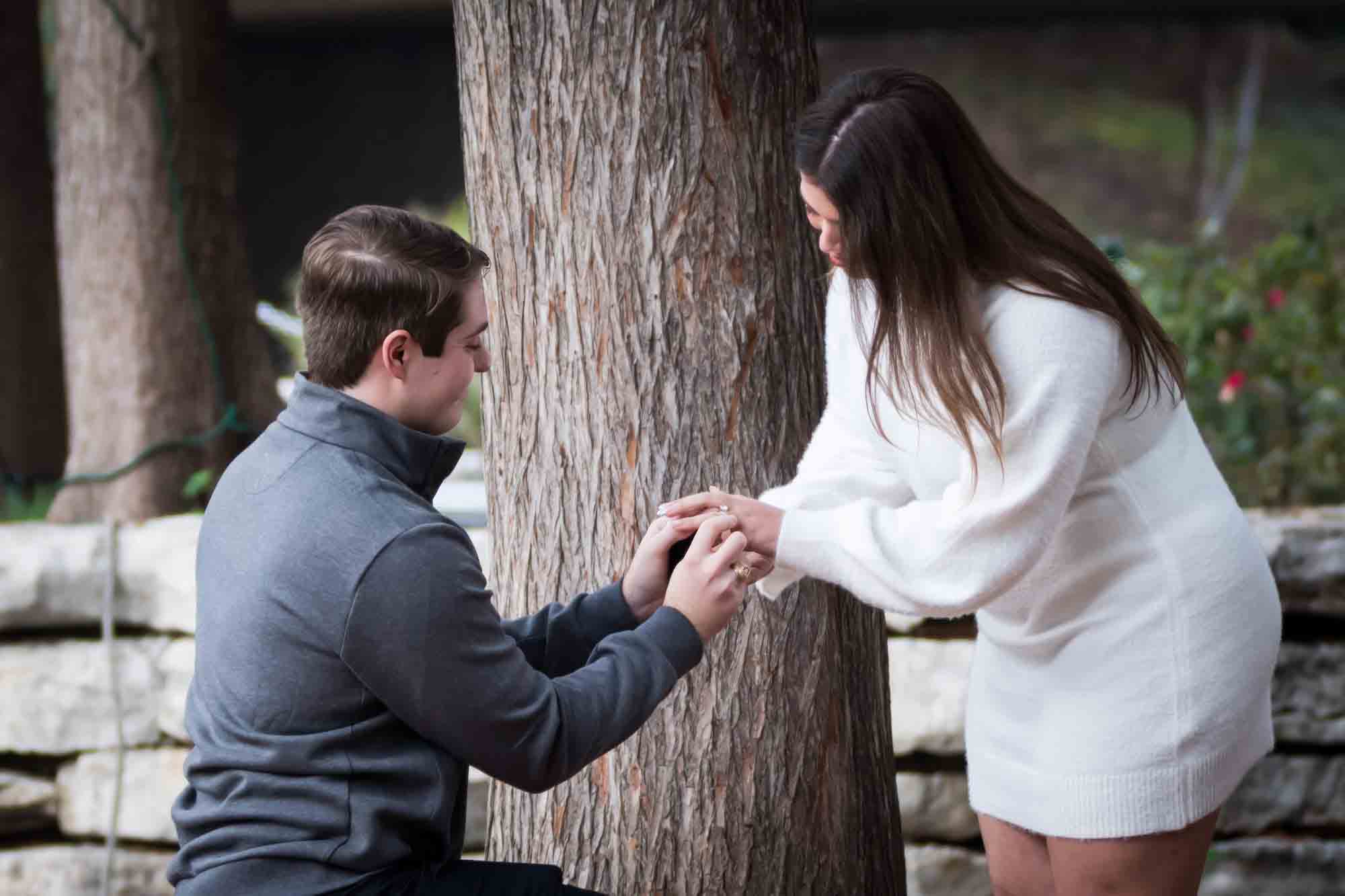 Man proposing on one knee during a surprise proposal at the Pearl