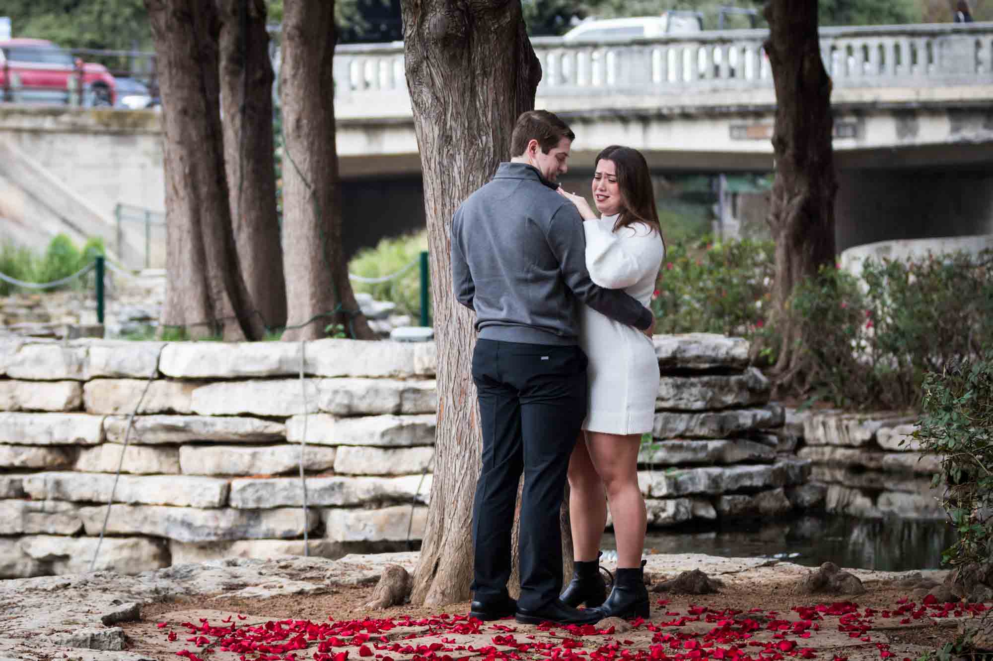 Couple hugging on little island during a surprise proposal at the Pearl