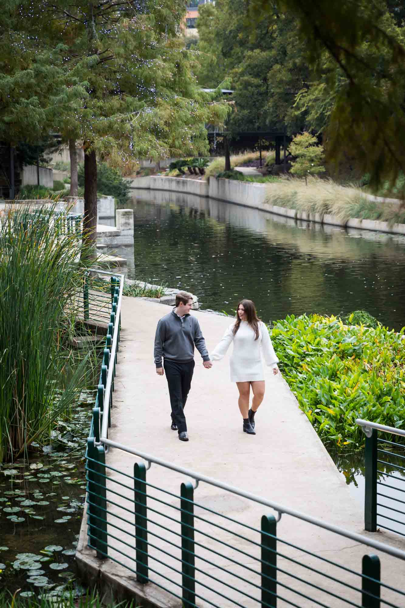 Couple walking on Riverwalk pathway for an article on rain backup photo locations at the Pearl in San Antonio