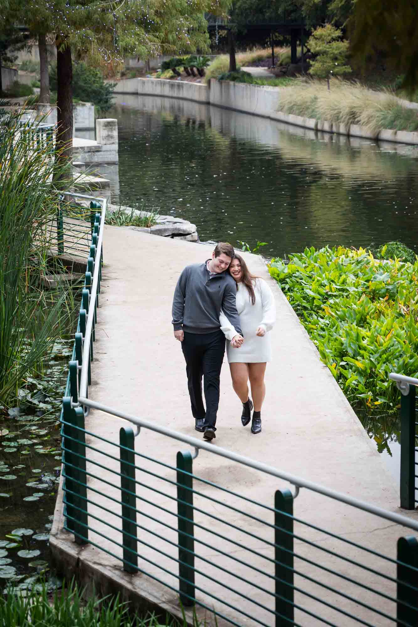 Couple walking on Riverwalk pathway for an article on rain backup photo locations at the Pearl in San Antonio