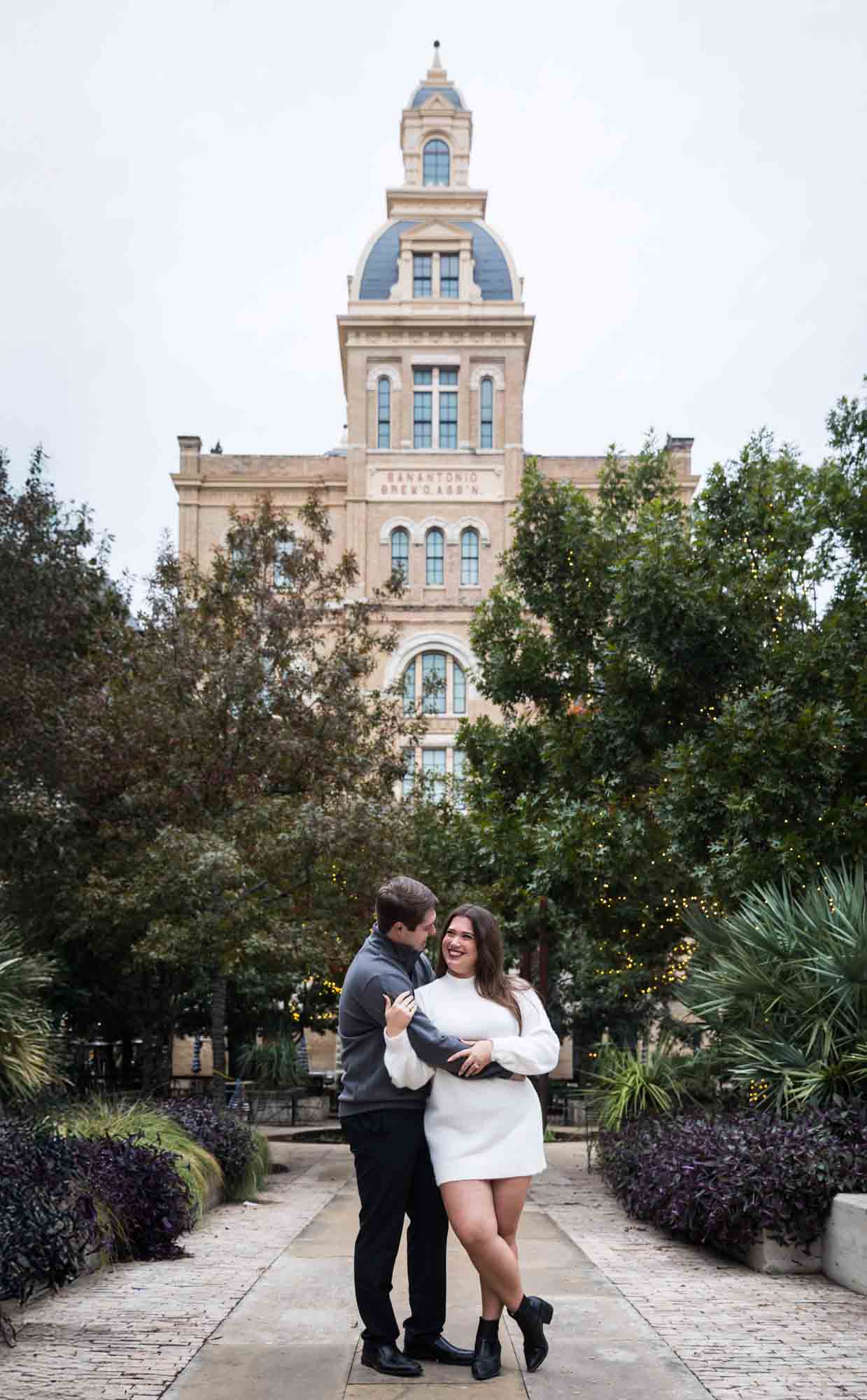 Couple hugging in front of Pearl tower building during a surprise proposal at the Pearl