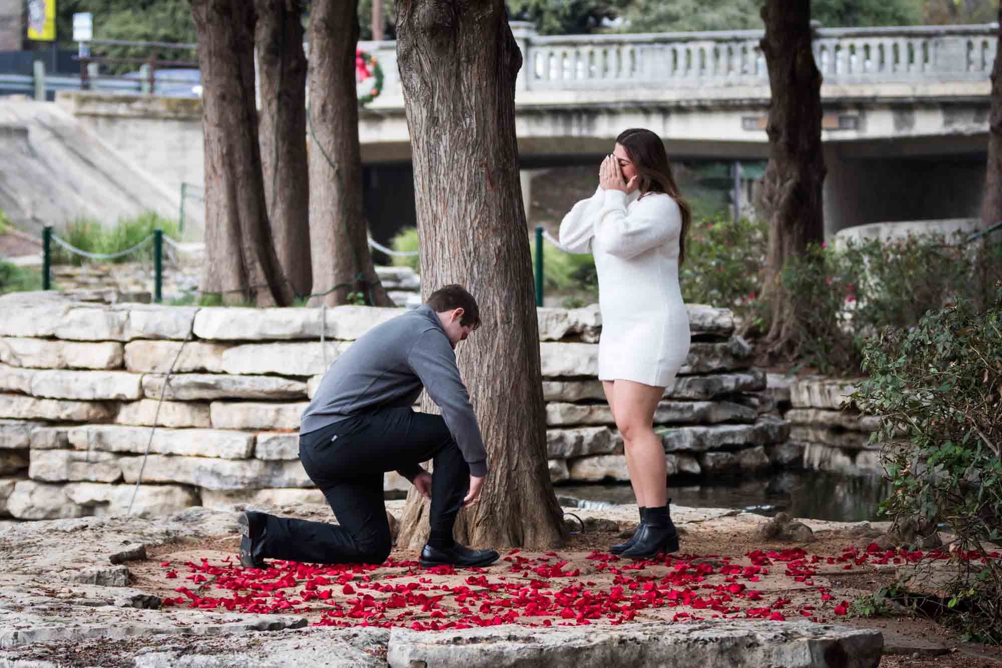 Man proposing on one knee during a surprise proposal at the Pearl