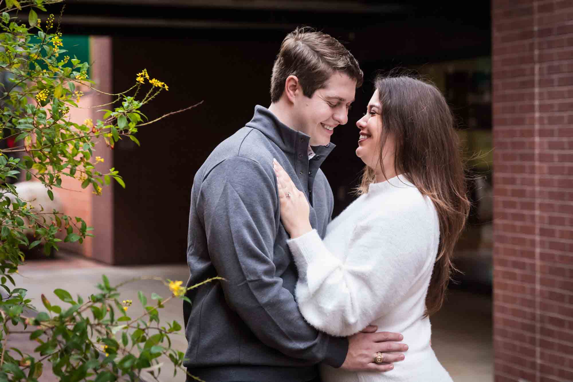 Couple hugging in alleyway during an engagement photo shoot at the Pearl