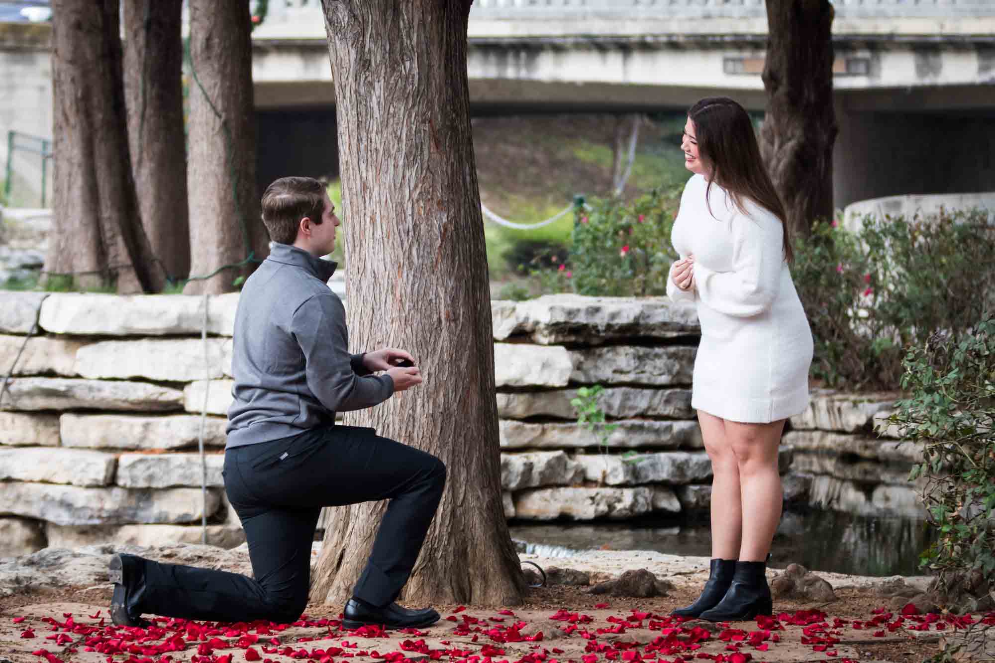 Man proposing on one knee during a surprise proposal at the Pearl