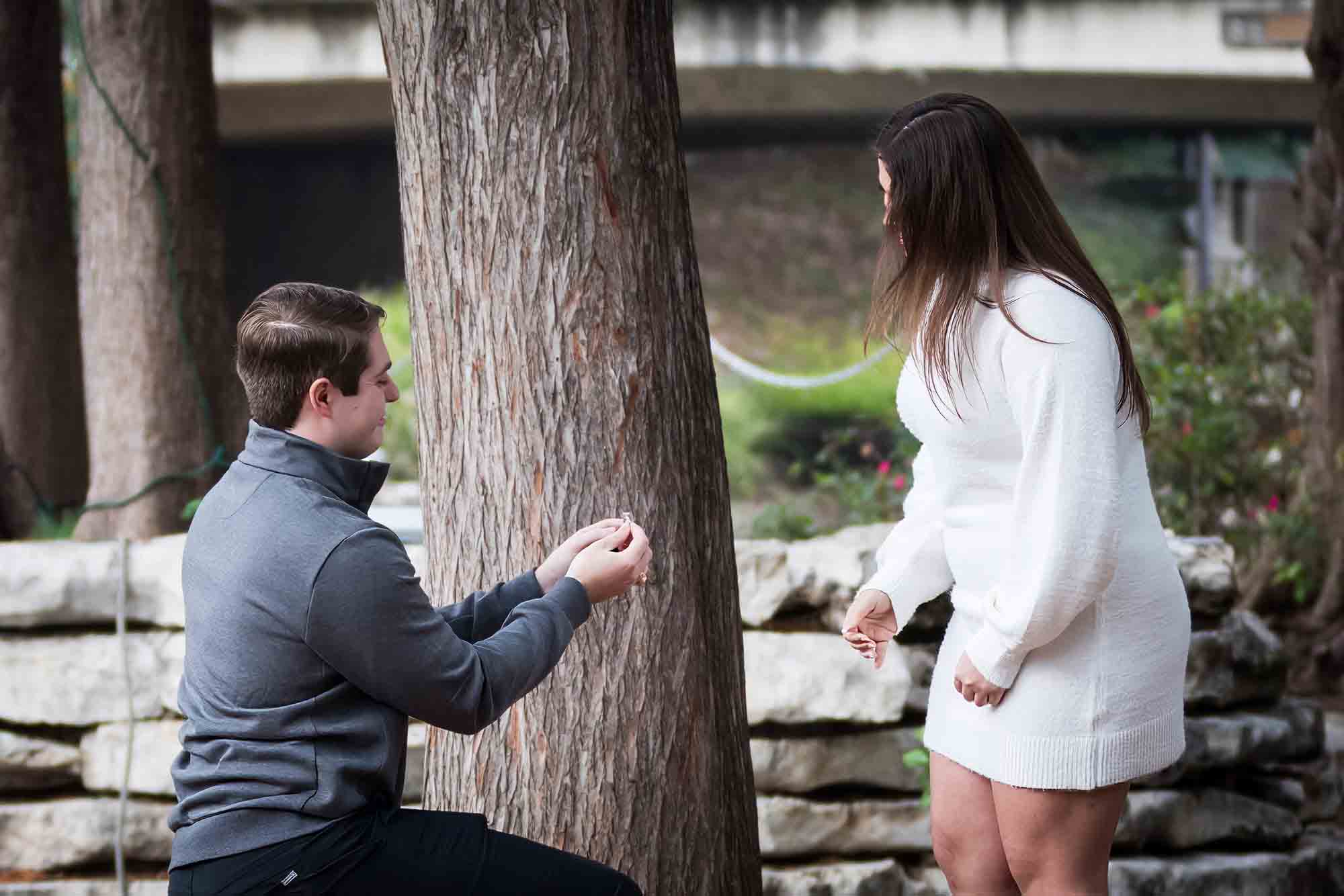 Man proposing on one knee during a surprise proposal at the Pearl