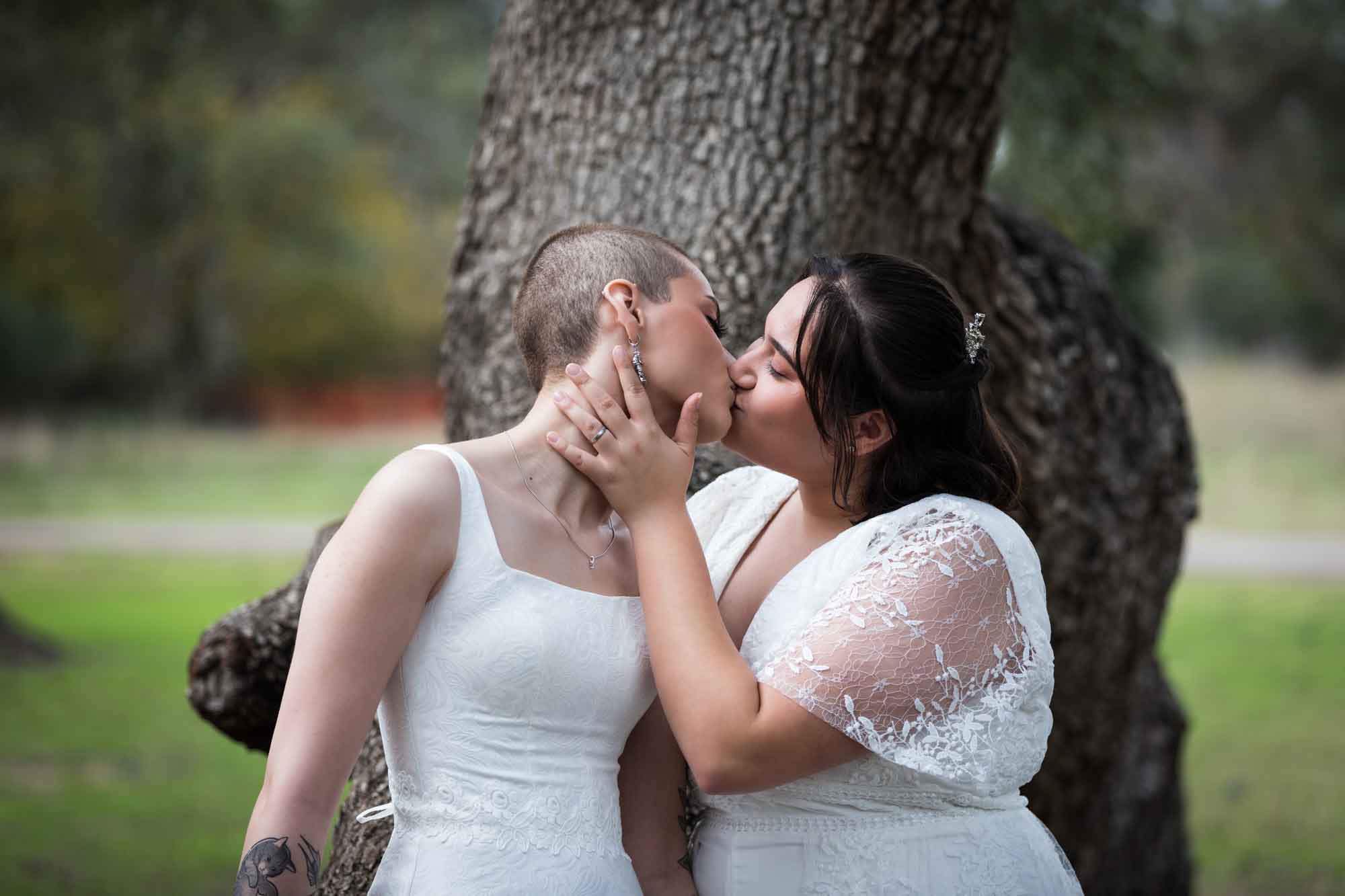 Walker Ranch Park wedding photos of two brides dressed in white kissing with tree in background