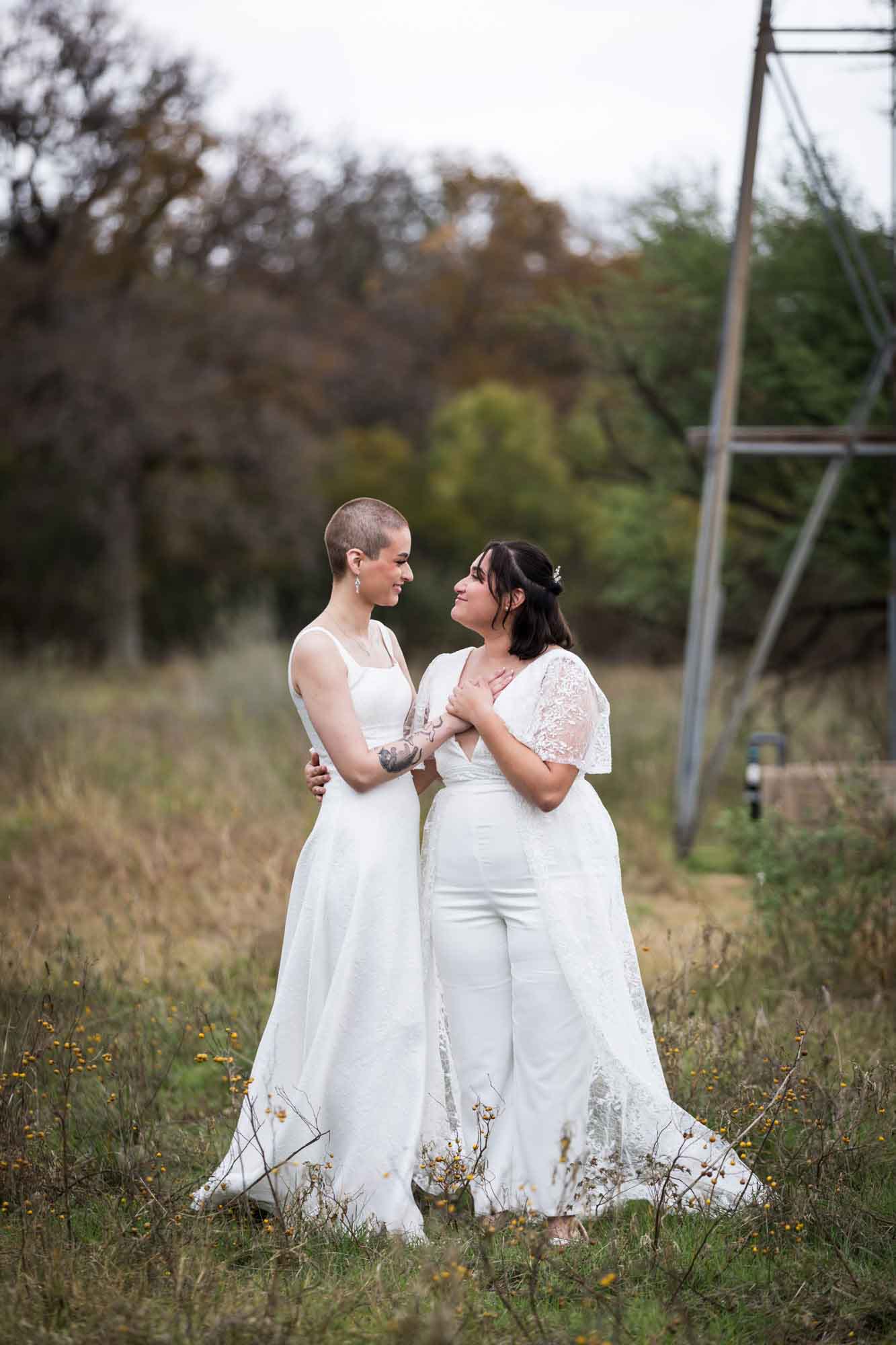 Walker Ranch Park wedding photos of two brides dressed in white and hugging in grass