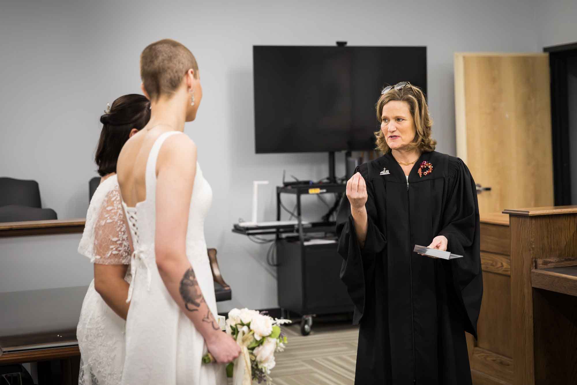 Judge speaking during wedding ceremony to two brides at Bexar County Courthouse Precinct 3