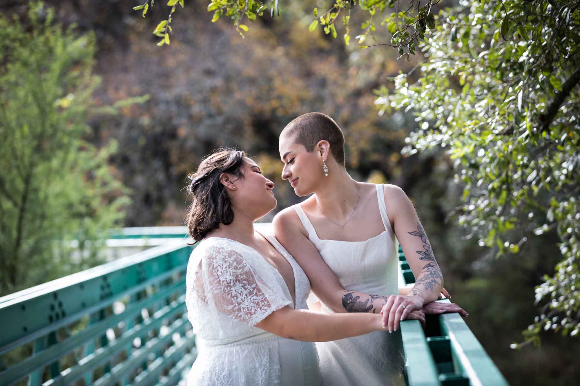 Walker Ranch Park wedding photos of two brides dressed in white kissing on green bridge