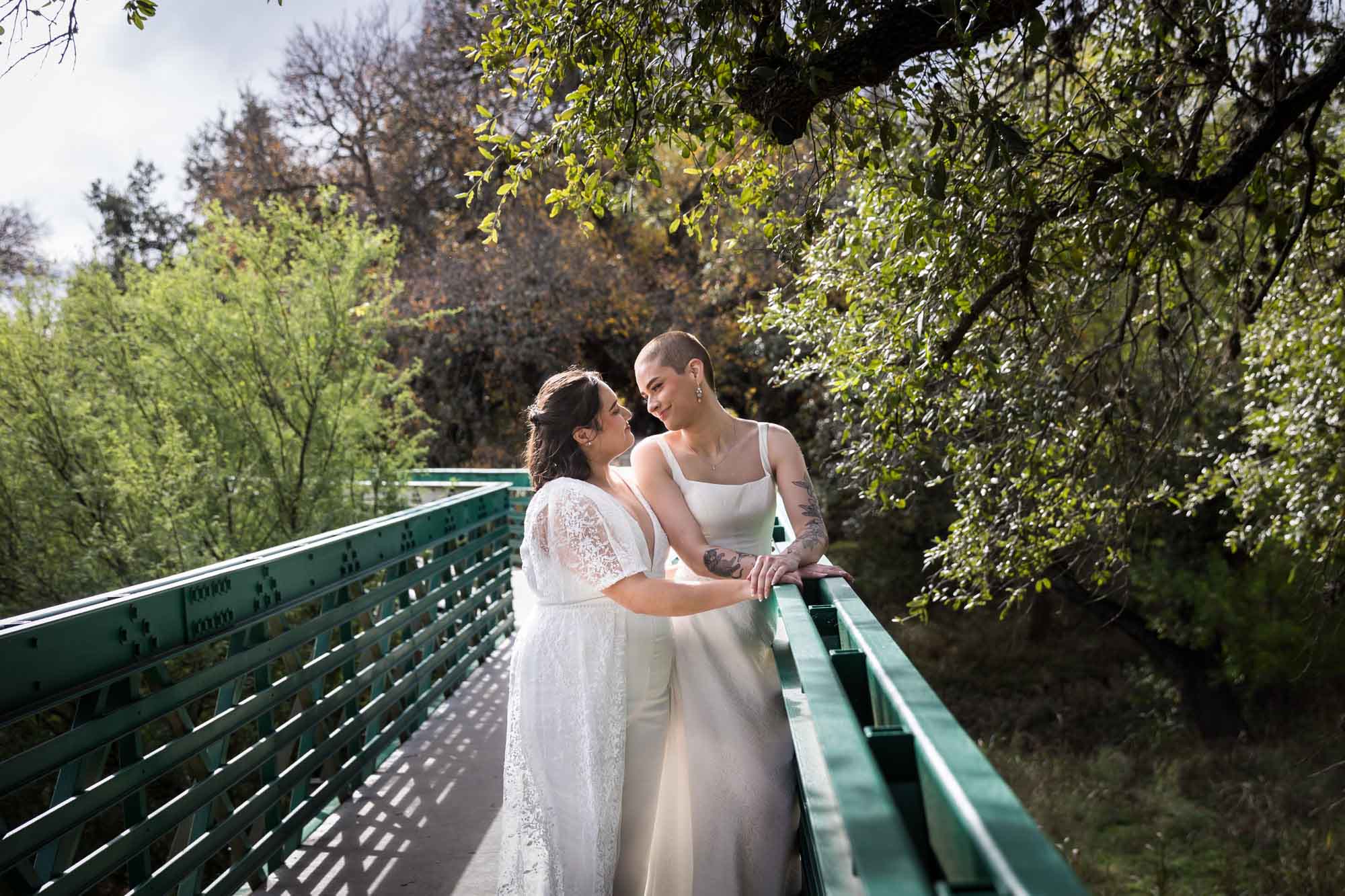 Walker Ranch Park wedding photos of two brides dressed in white hugging on green bridge