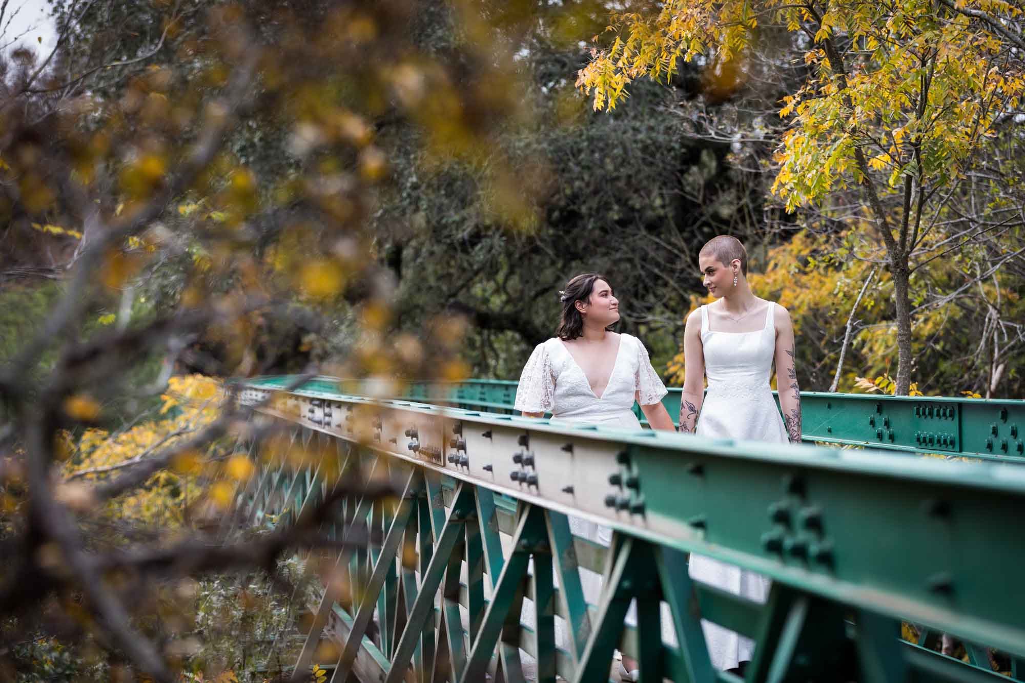 Walker Ranch Park wedding photos of two brides dressed in white walking along green bridge