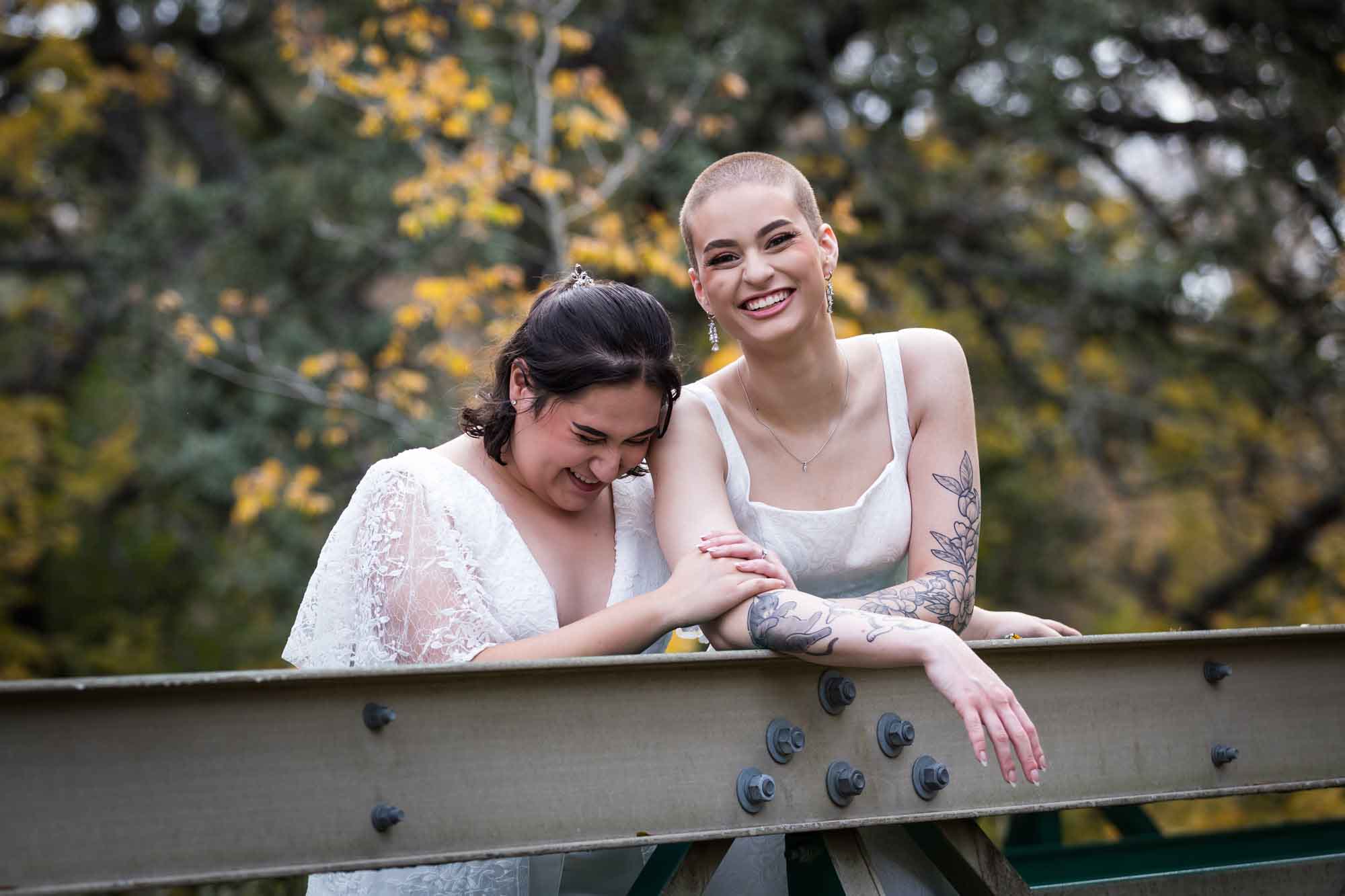 Walker Ranch Park wedding photos of two brides dressed in white leaning on bridge railing