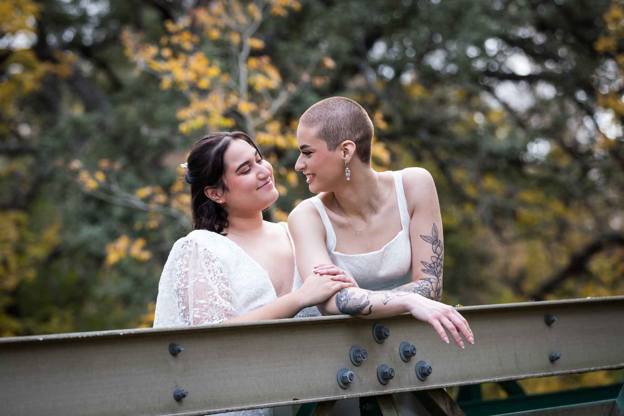 Walker Ranch Park wedding photos of two brides dressed in white leaning on bridge railing