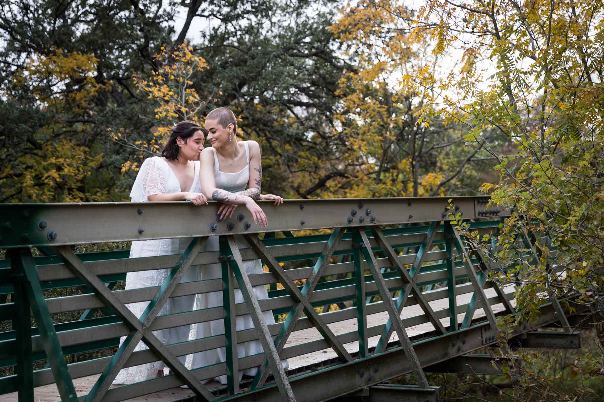 Walker Ranch Park wedding photos of two brides dressed in white leaning on bridge railing