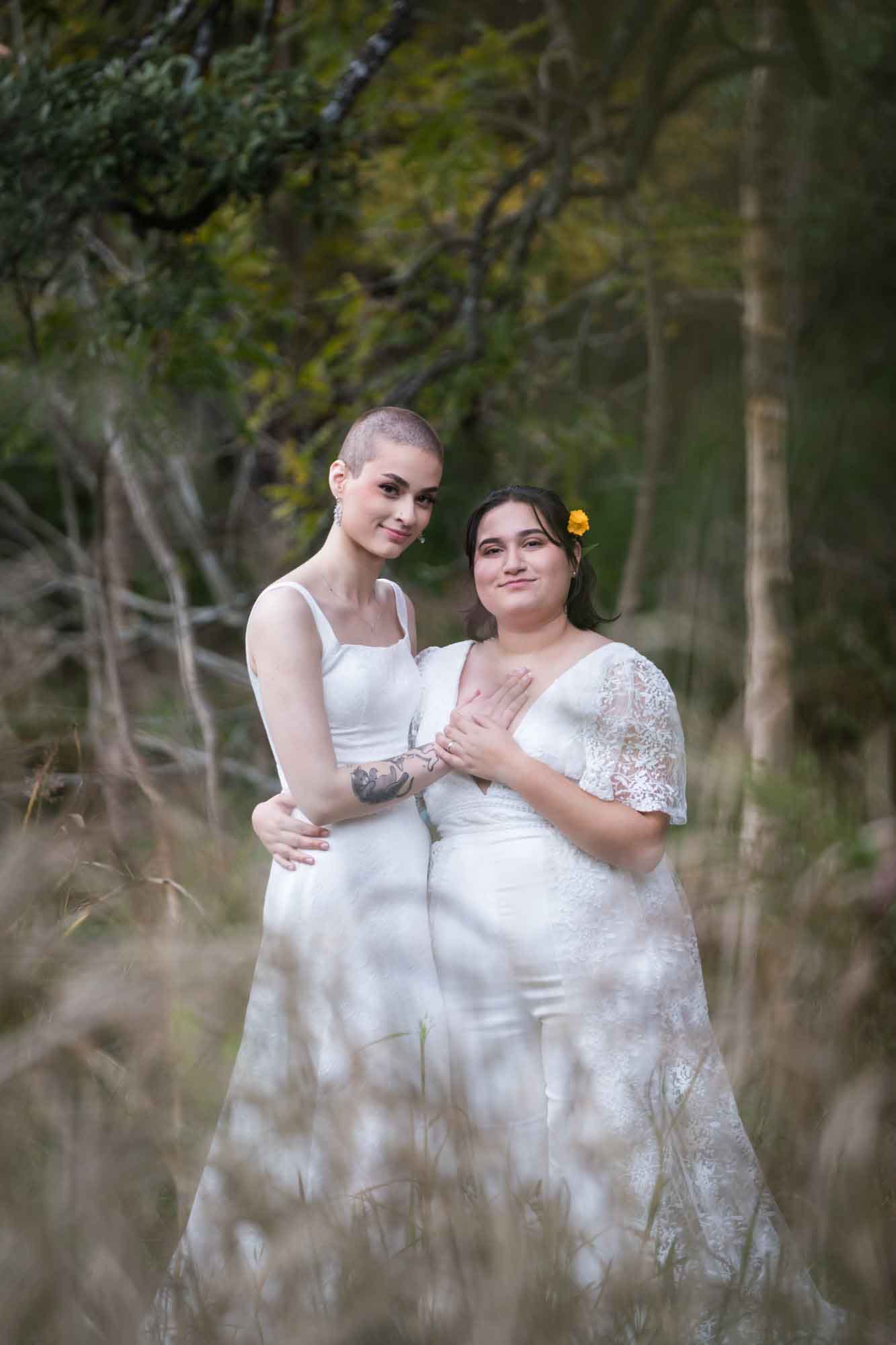 Walker Ranch Park wedding photos of two brides dressed in white standing in front of forest and grass