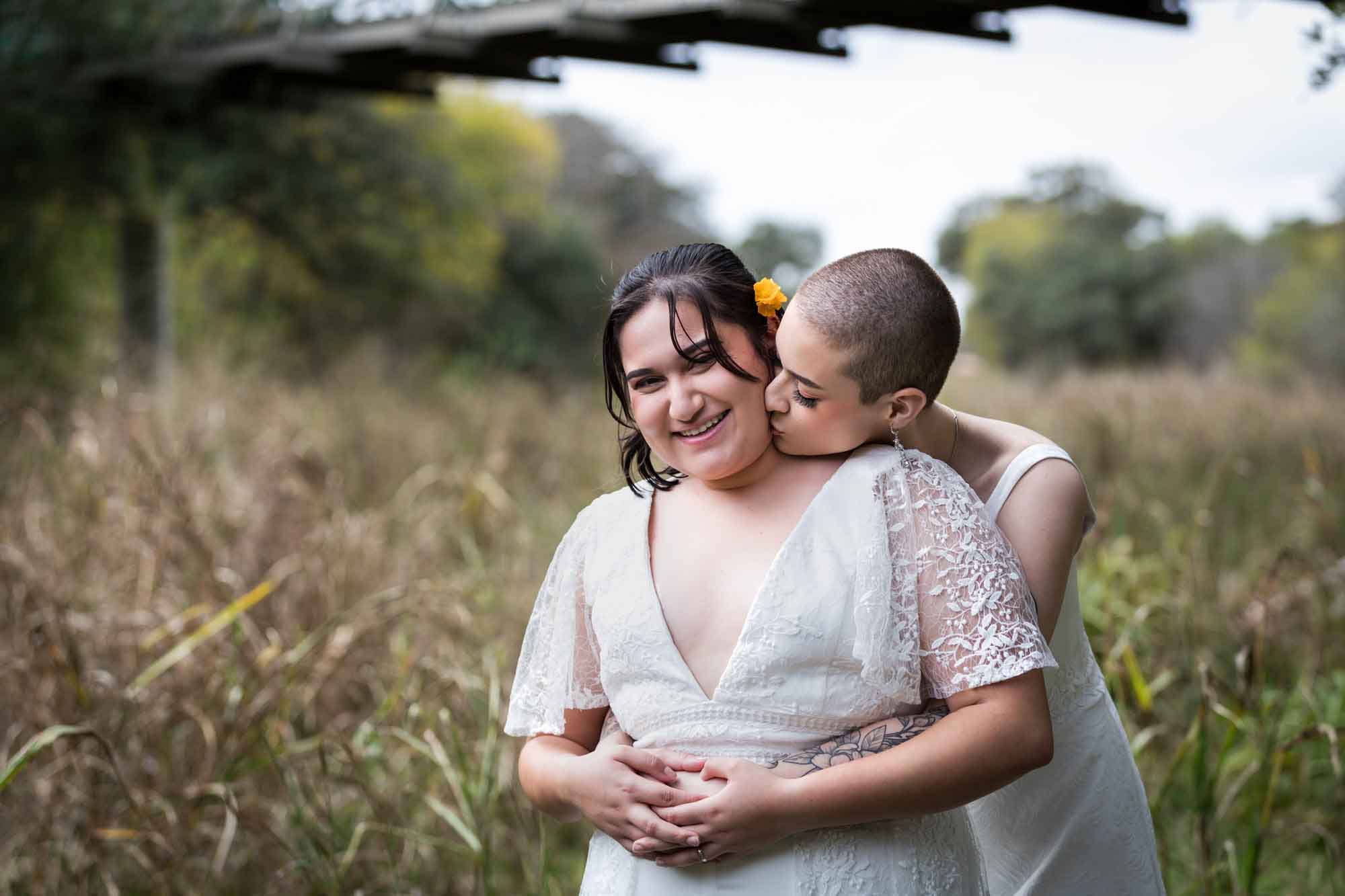 Walker Ranch Park wedding photos of two brides dressed in white kissing in grass