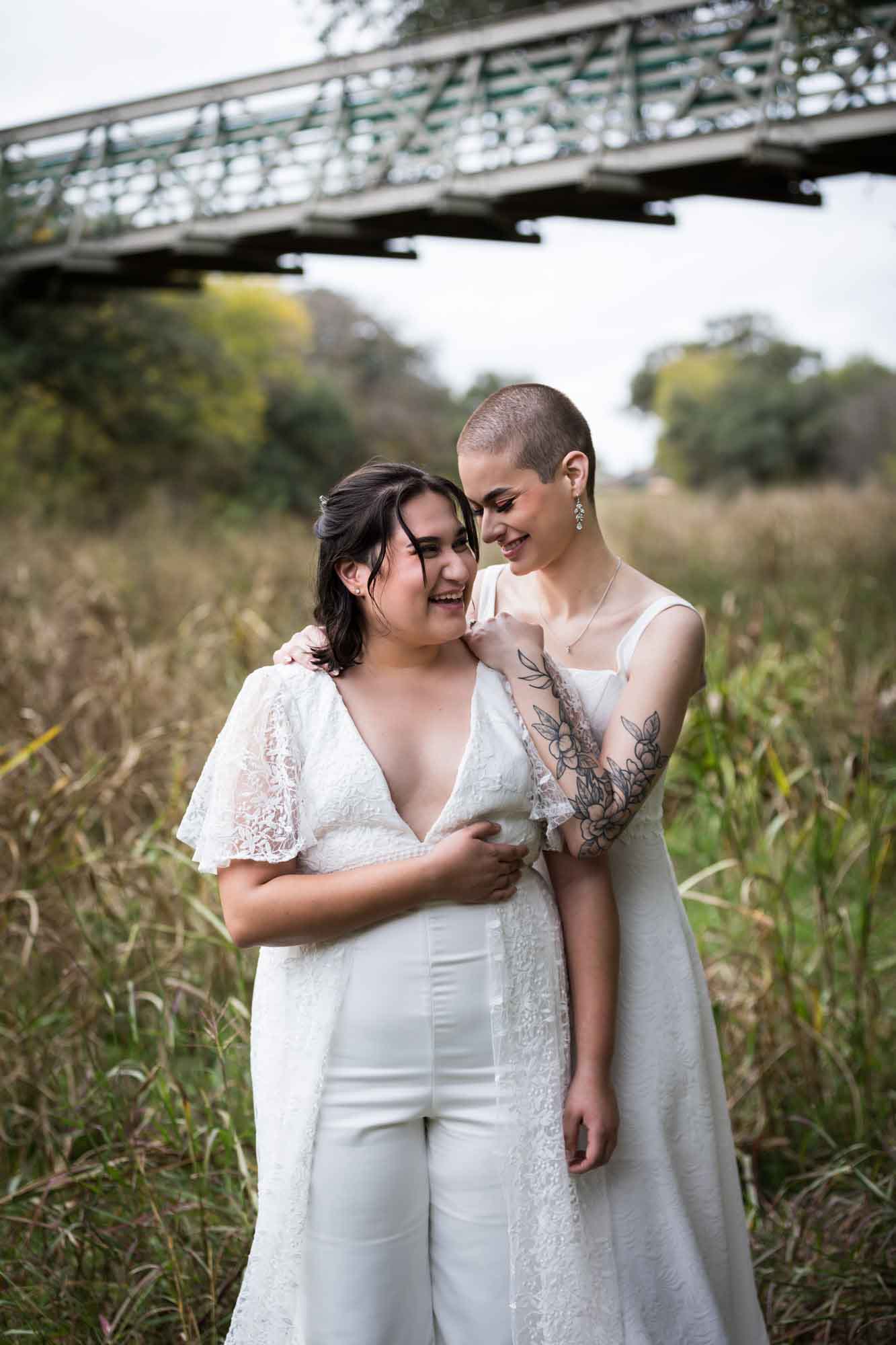 Walker Ranch Park wedding photos of two brides dressed in white hugging in grass