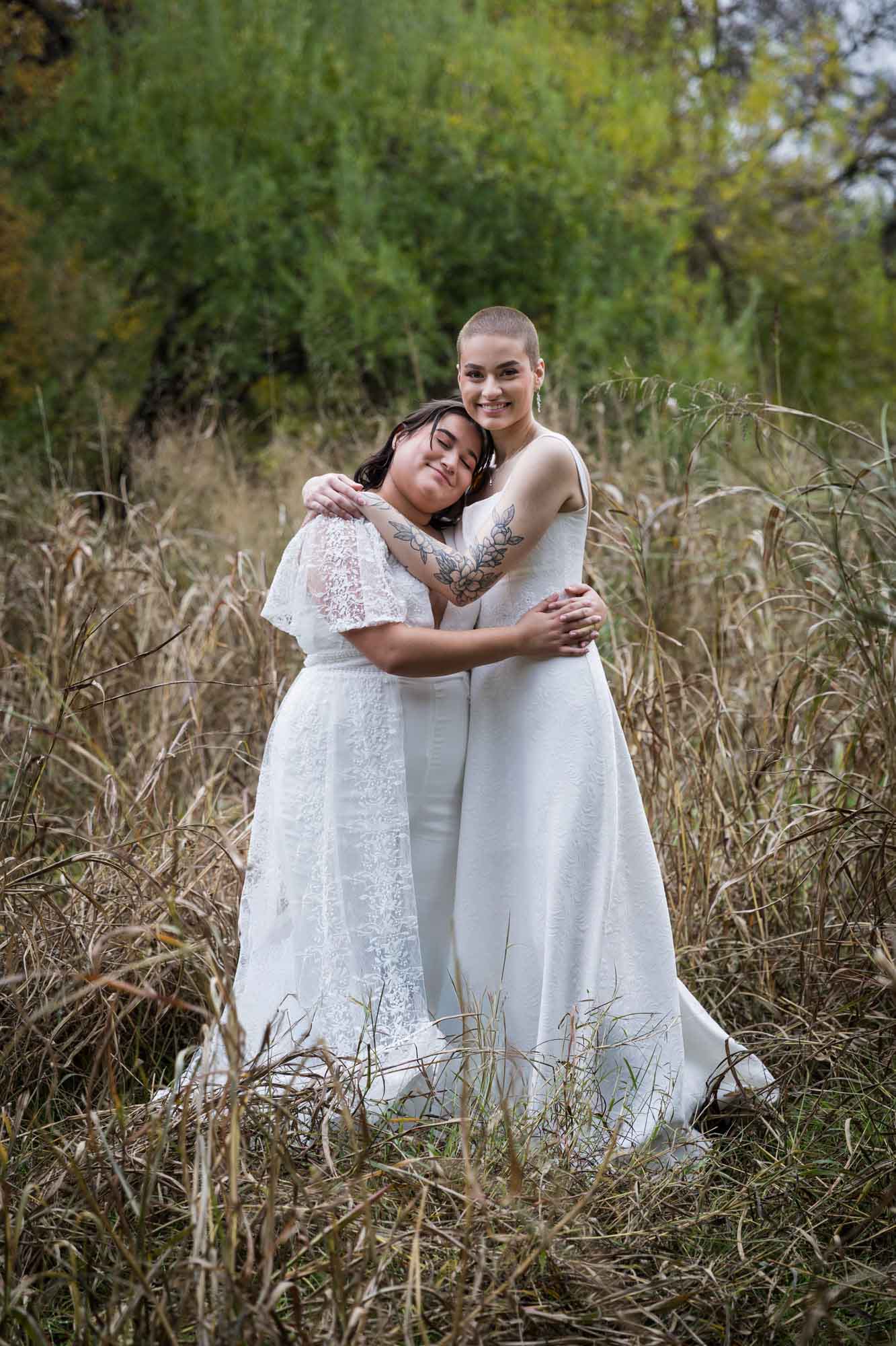 Walker Ranch Park wedding photos of two brides dressed in white hugging in grass