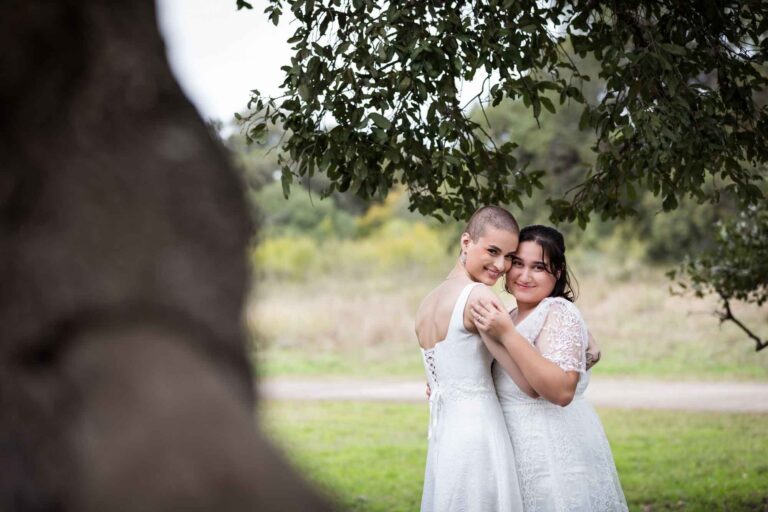 Walker Ranch Park wedding photos of two brides dressed in white hugging under a tree