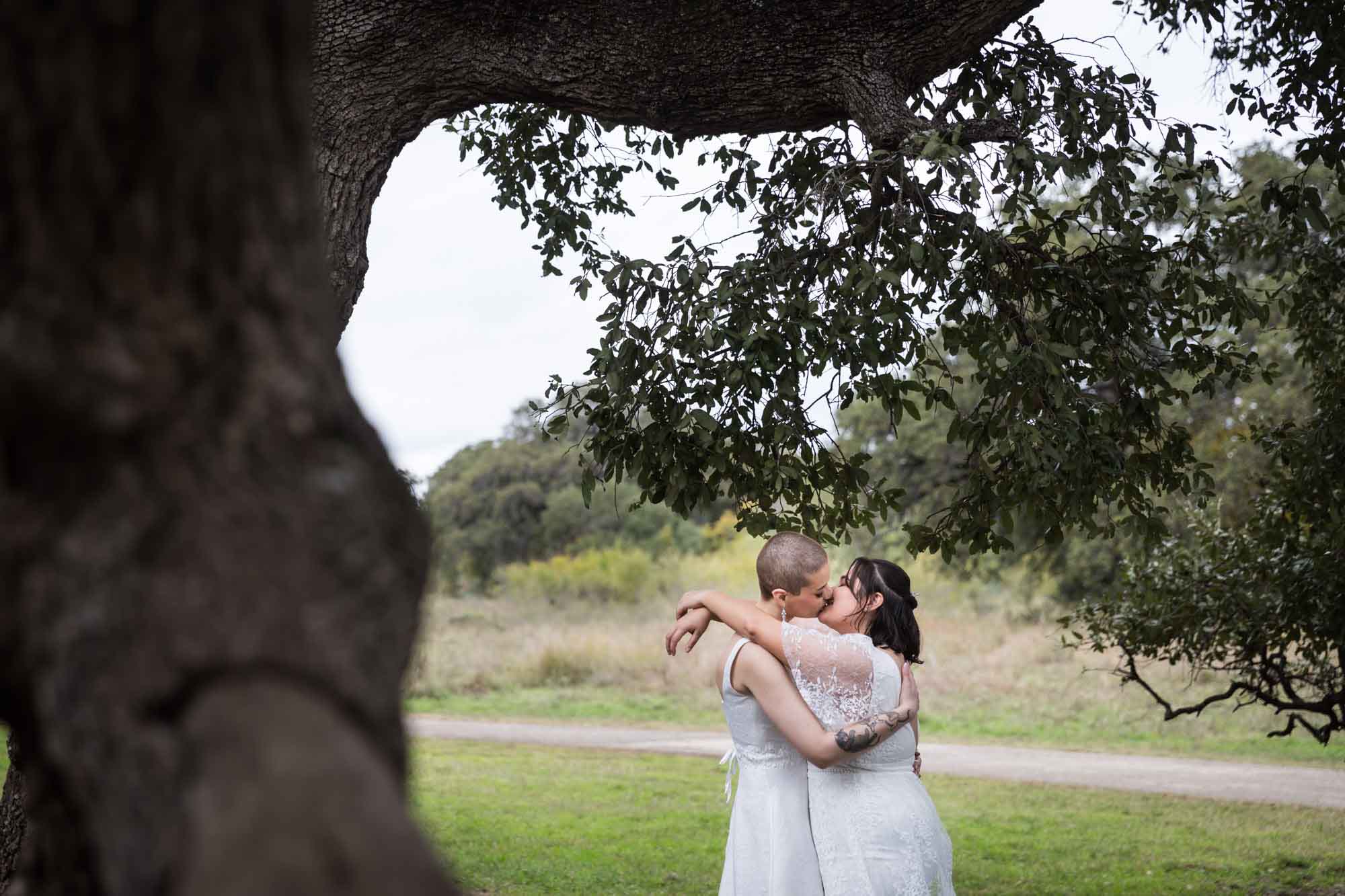 Walker Ranch Park wedding photos of two brides dressed in white kissing under a tree