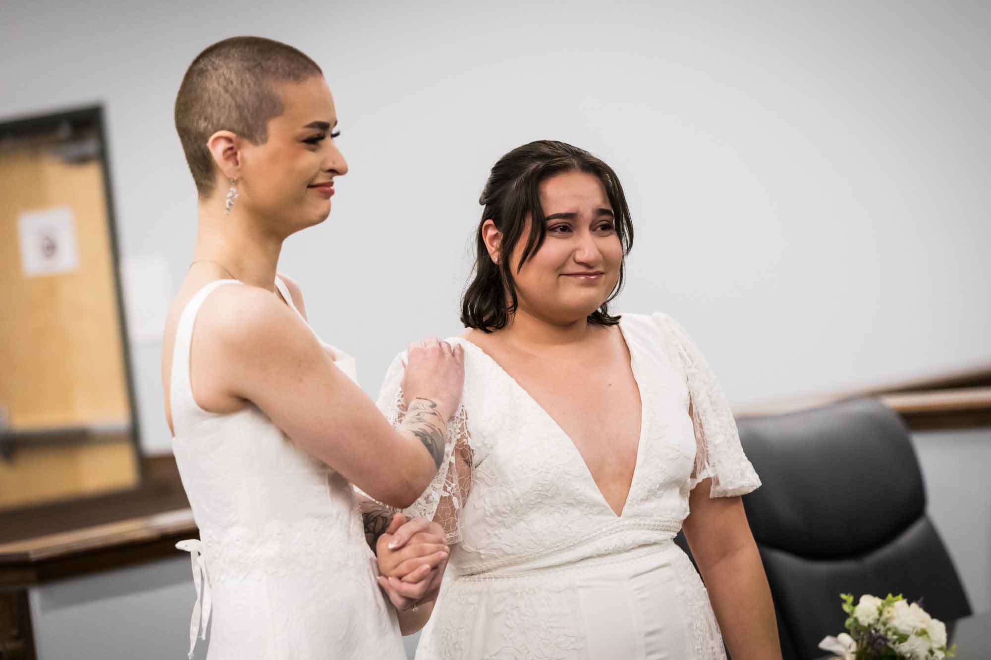 Two brides dressed in white during wedding ceremony at Bexar County Courthouse Precinct 3