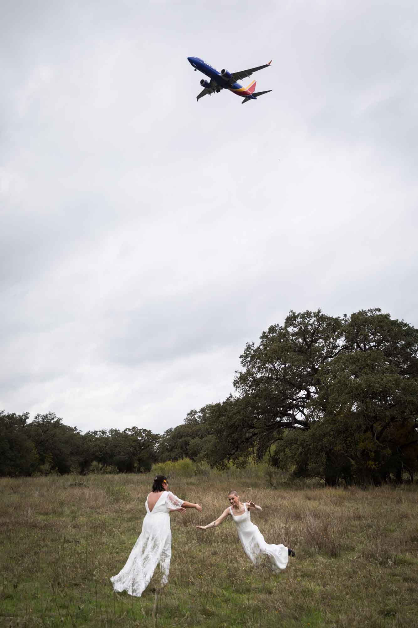 Walker Ranch Park wedding photos of two brides falling in the grass with a plane overhead