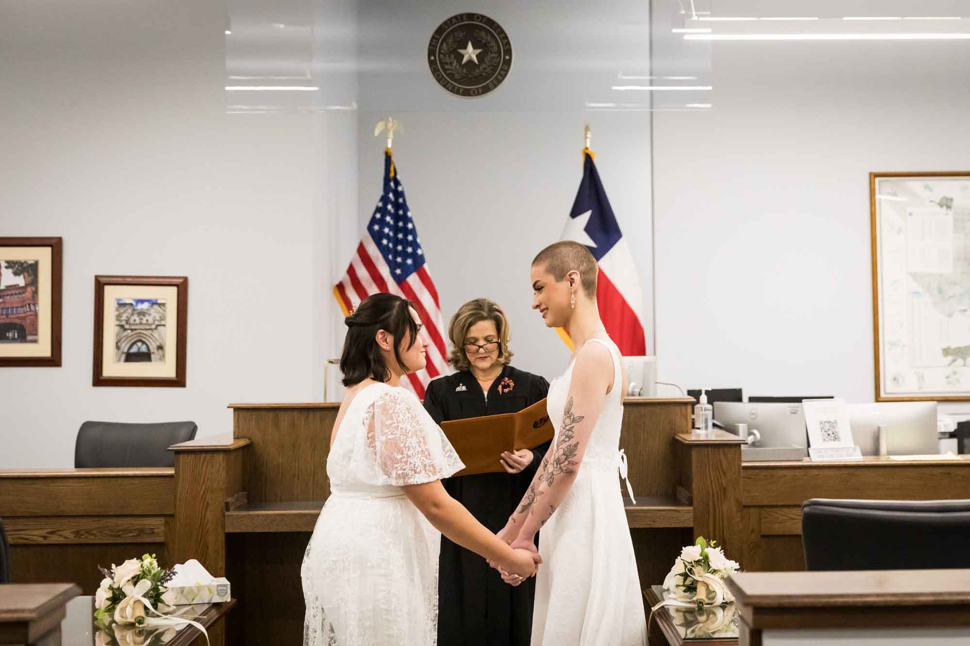 Two brides holding hands during wedding ceremony at Bexar County Courthouse Precinct 3