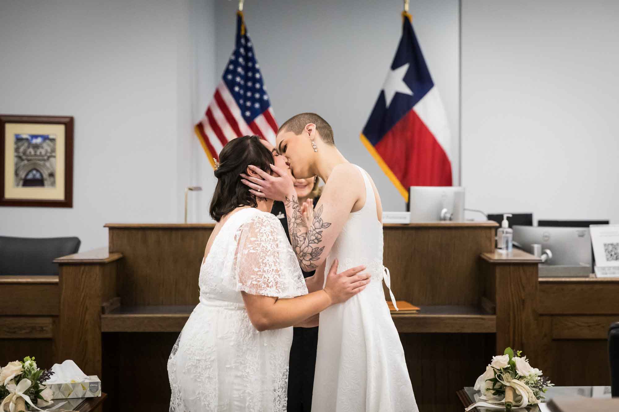 Two brides kissing during wedding ceremony at Bexar County Courthouse Precinct 3