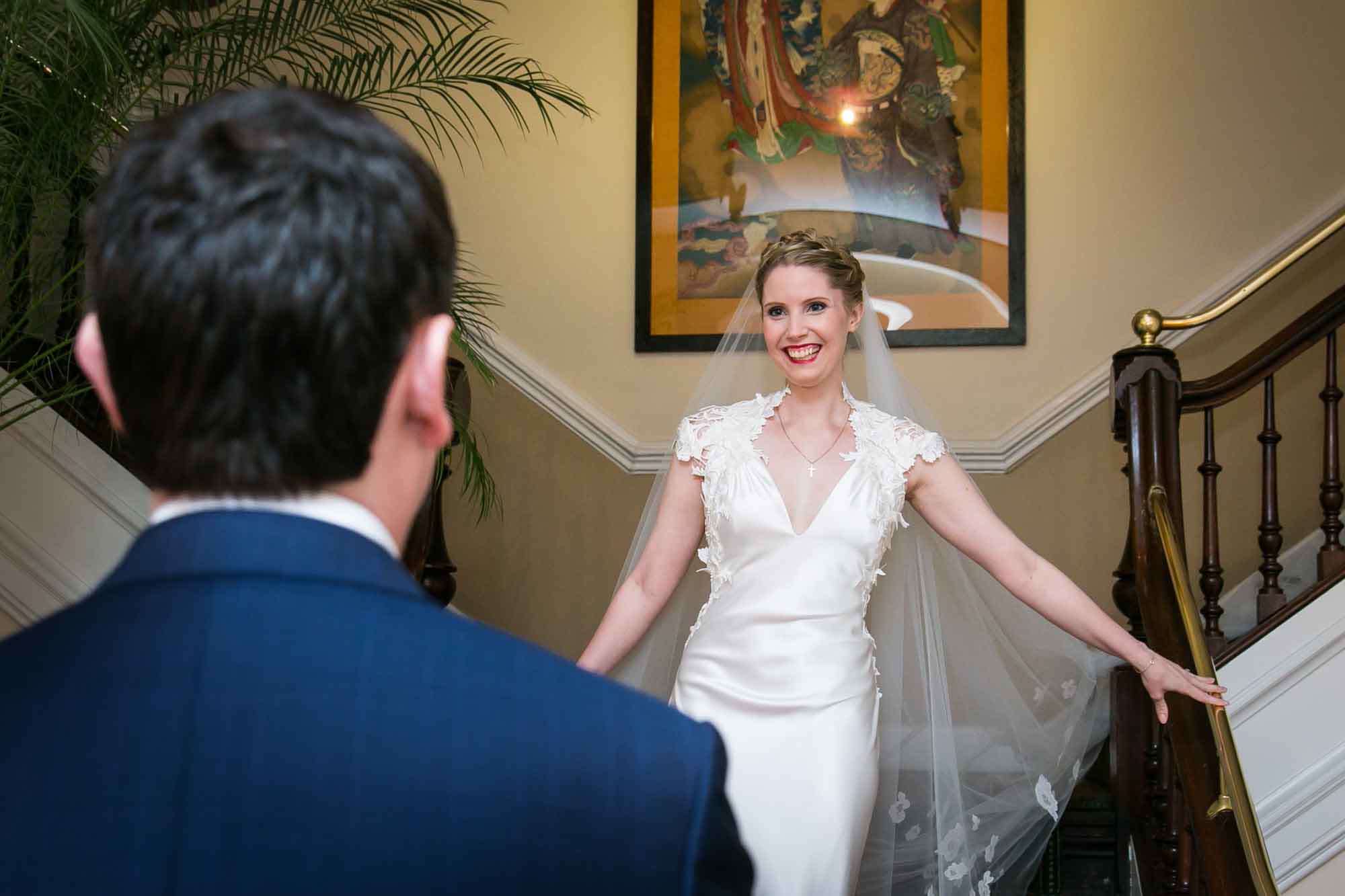 Bride coming down stairs during first look for article on pros and cons of first look