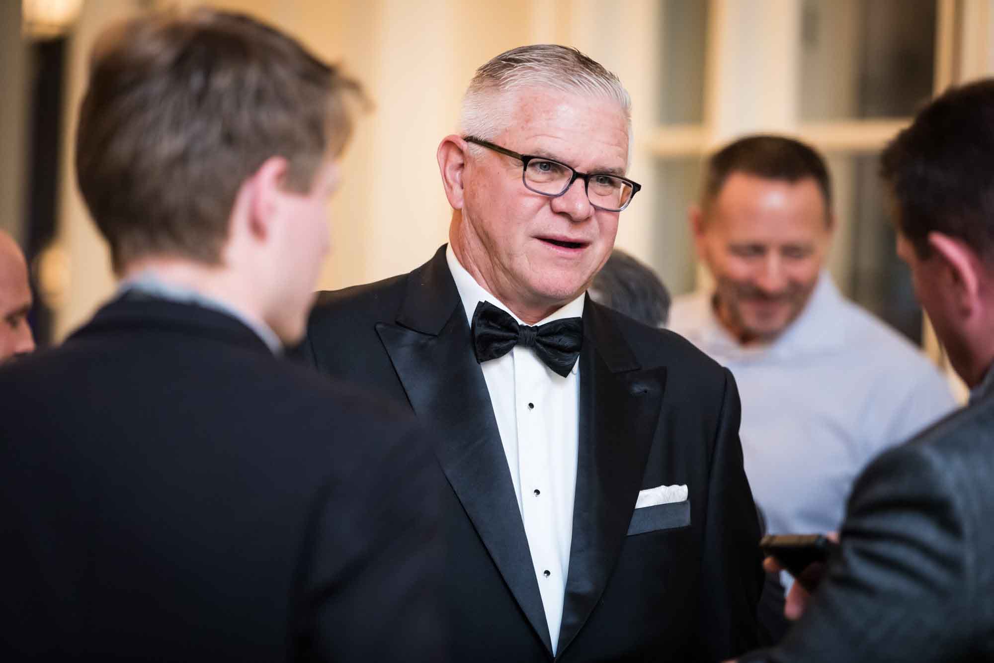 Man wearing black tuxedo, bow tie and glasses for an article on a St. Anthony Hotel corporate event