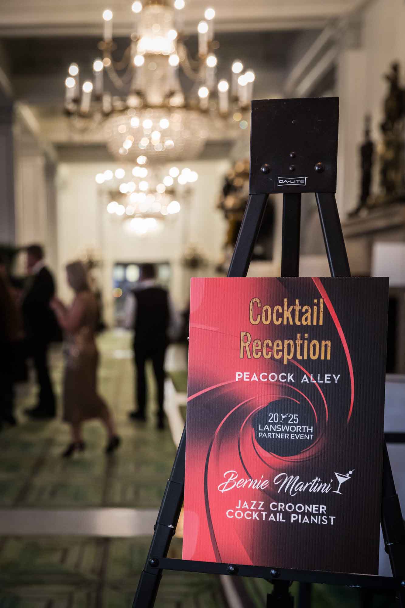 Sign for a cocktail reception with guests walking in background and glass chandeliers for an article on a St. Anthony Hotel corporate event