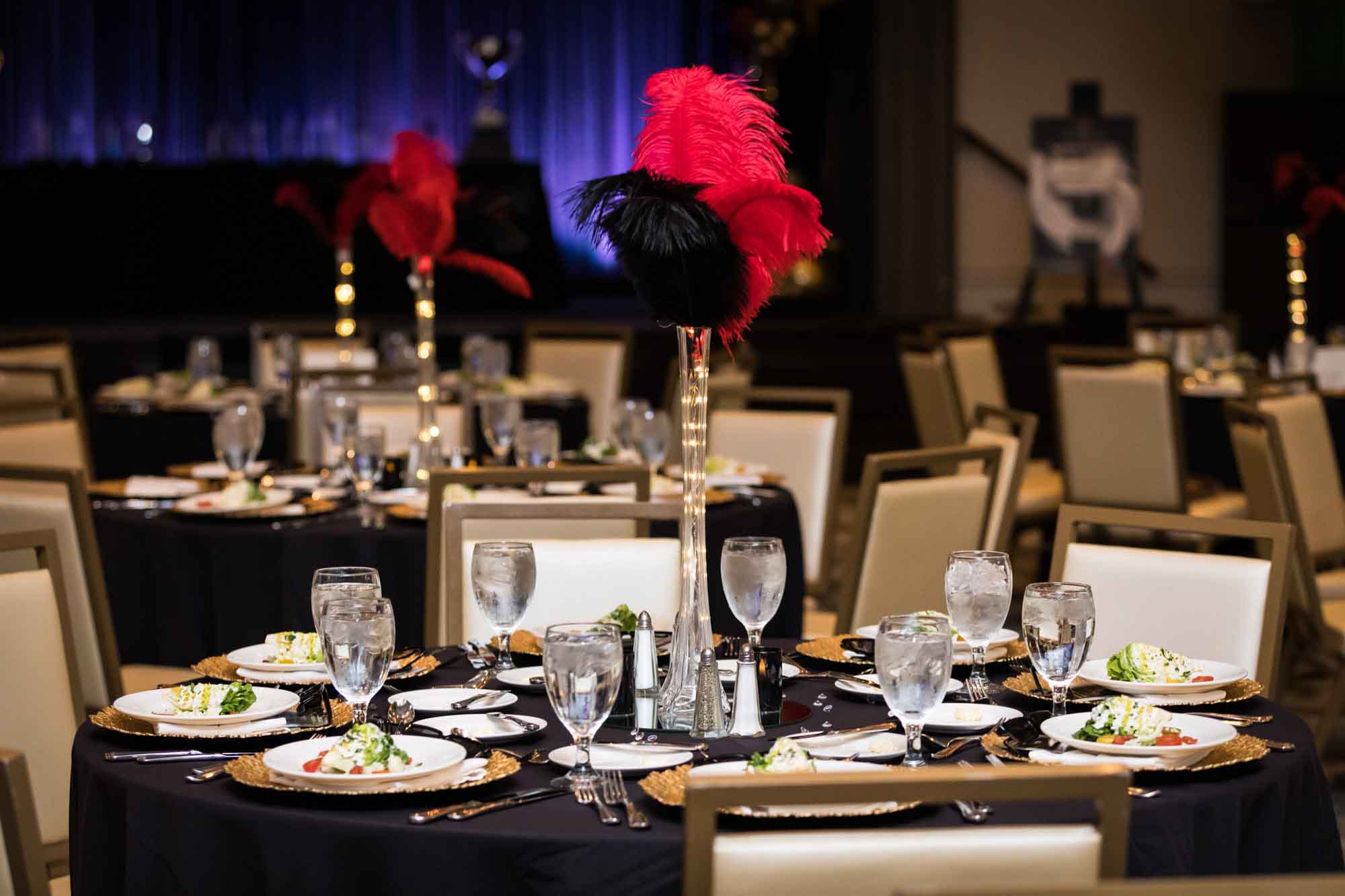 Tables set for dinner showing feather centerpieces for an article on a St. Anthony Hotel corporate event