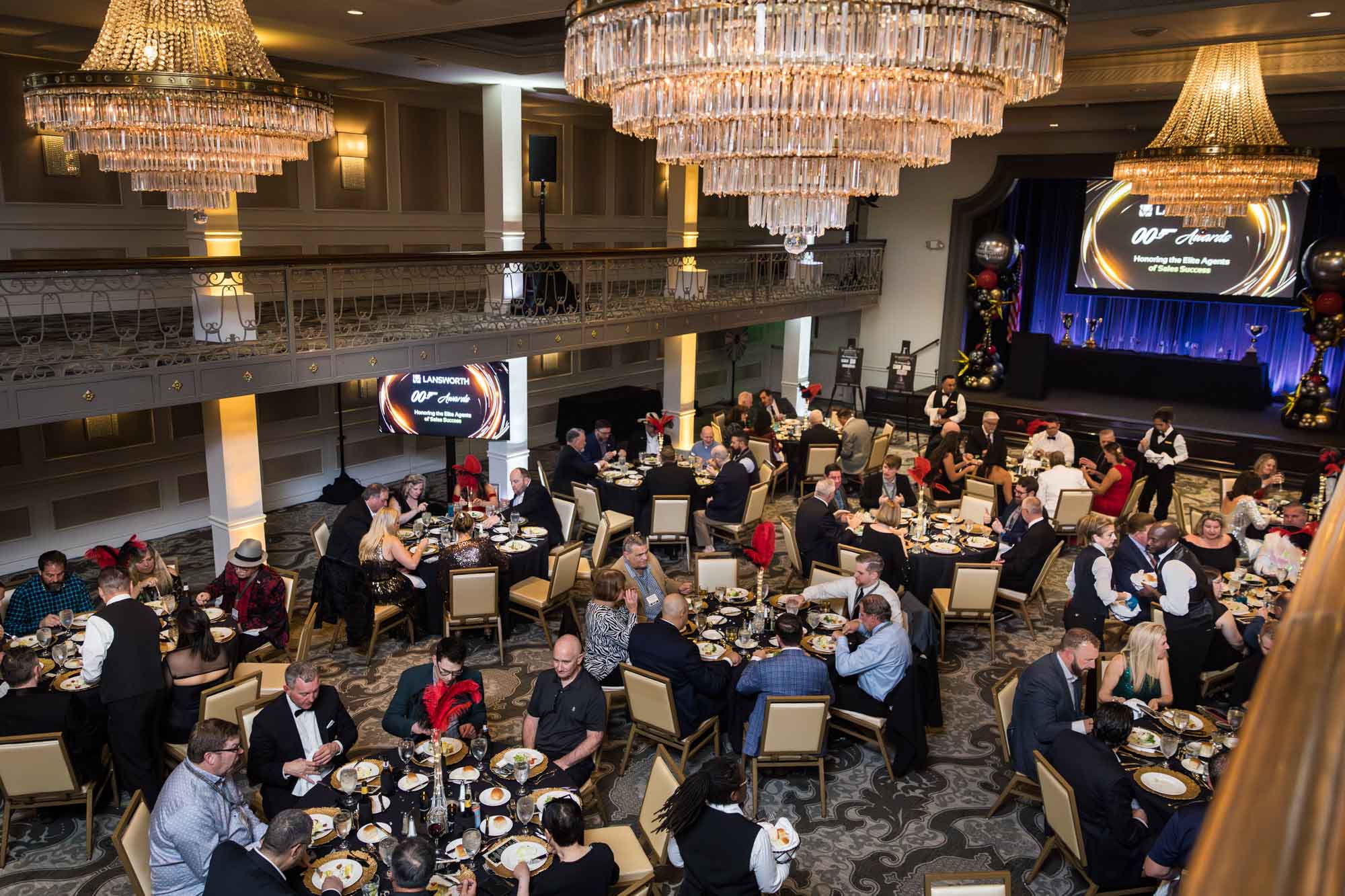 Wide view of guests seated at round tables during dinner in the Anacacho Ballroom under chandeliers for an article on a St. Anthony Hotel corporate event
