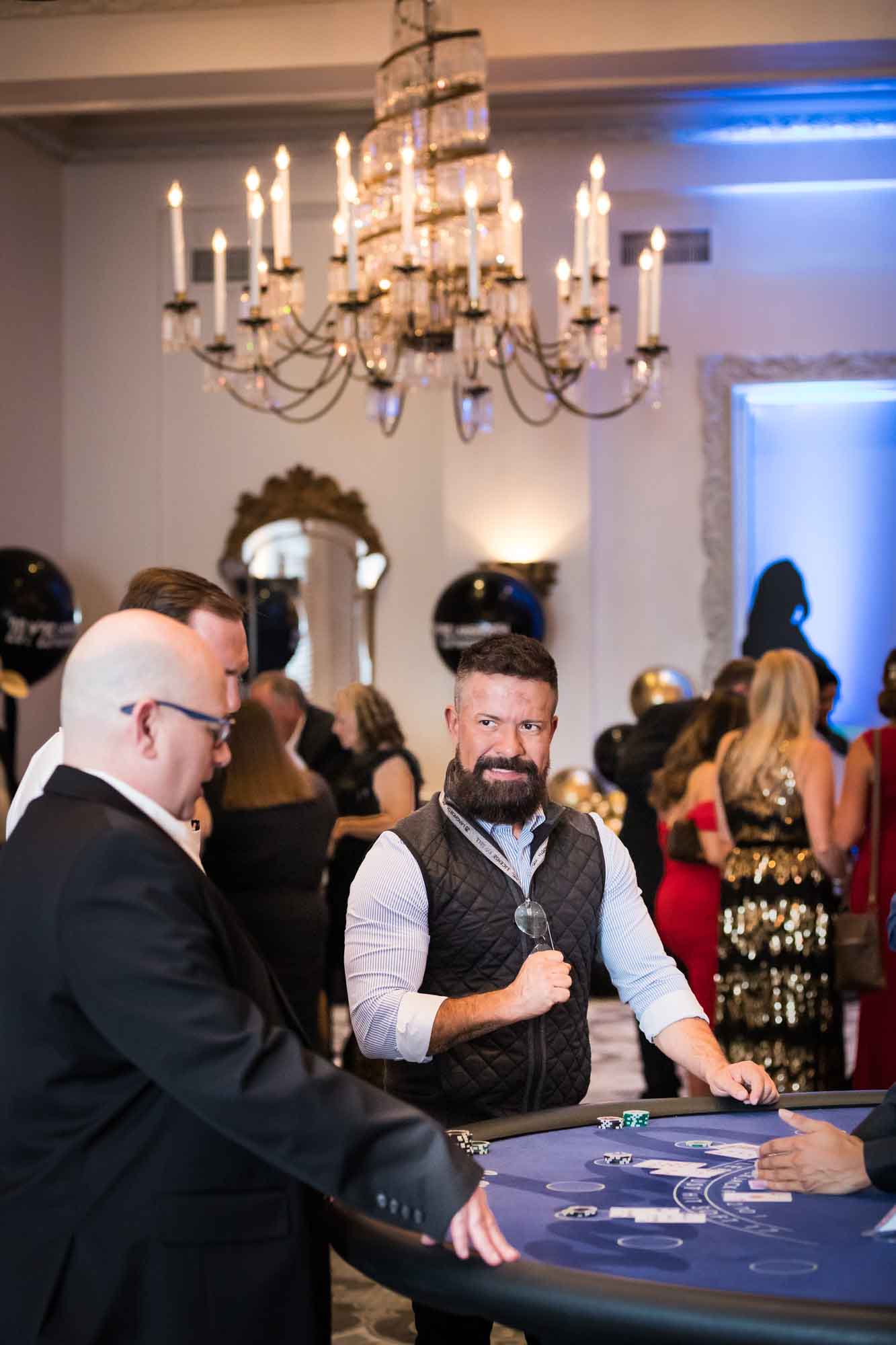 Man with clenched fist talking with two other male guests at a blackjack game table for an article on a St. Anthony Hotel corporate event