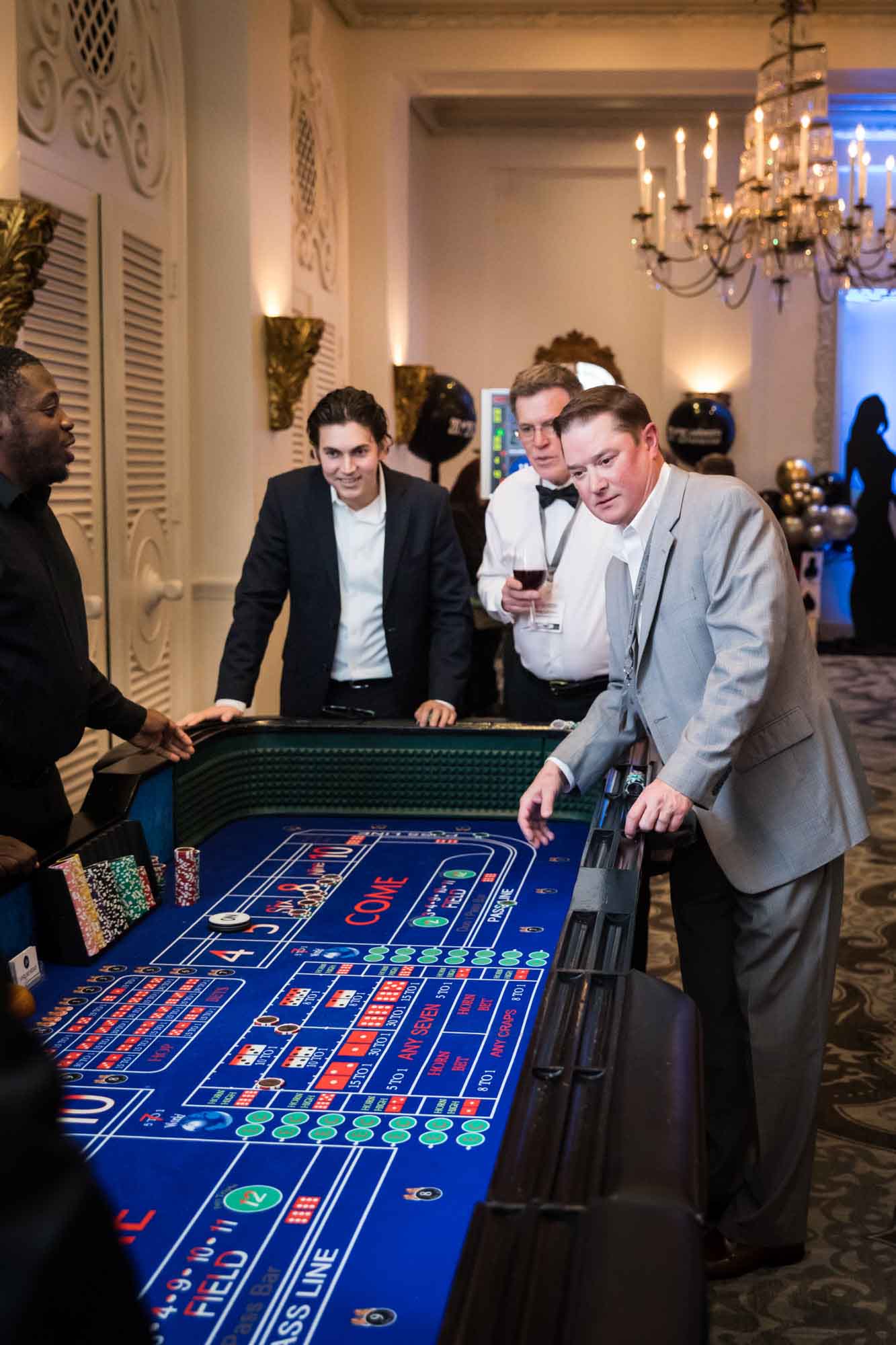 Three male guests looking down at blue craps table for an article on a St. Anthony Hotel corporate event