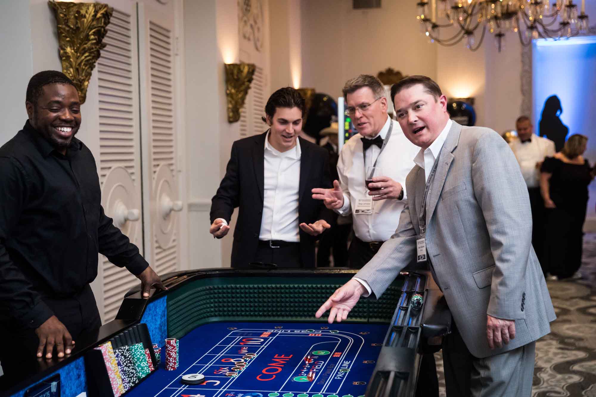 Guests throwing dice and looking at craps table for an article on a St. Anthony Hotel corporate event
