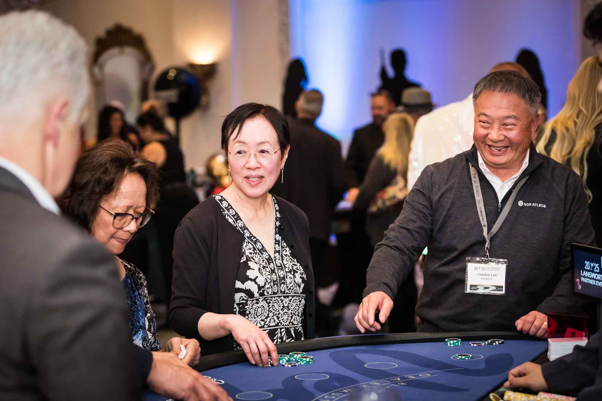 Guests laughing while standing around game table holding poker chips for an article on a St. Anthony Hotel corporate event
